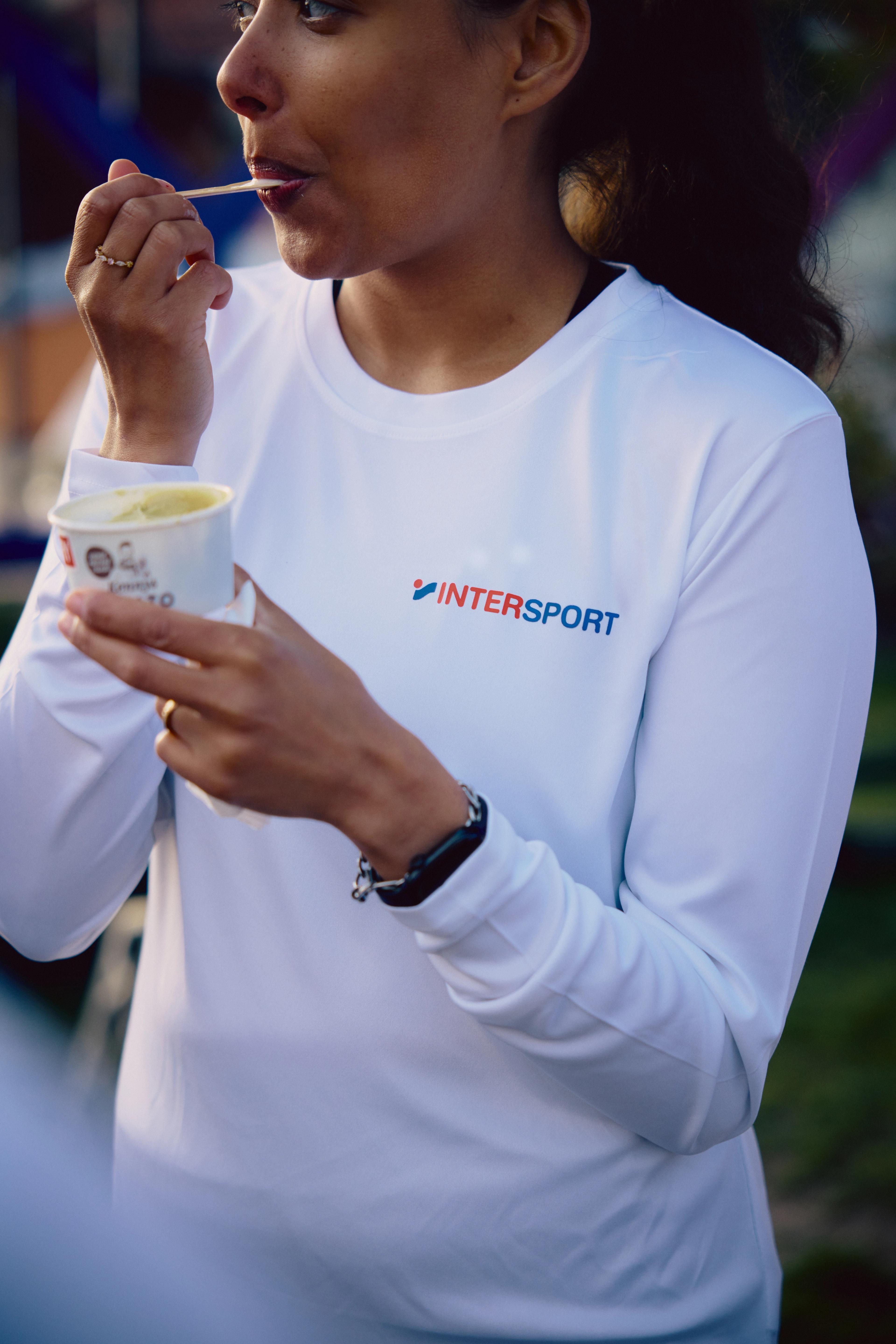 a woman wearing a white sweater with the word intersport on it