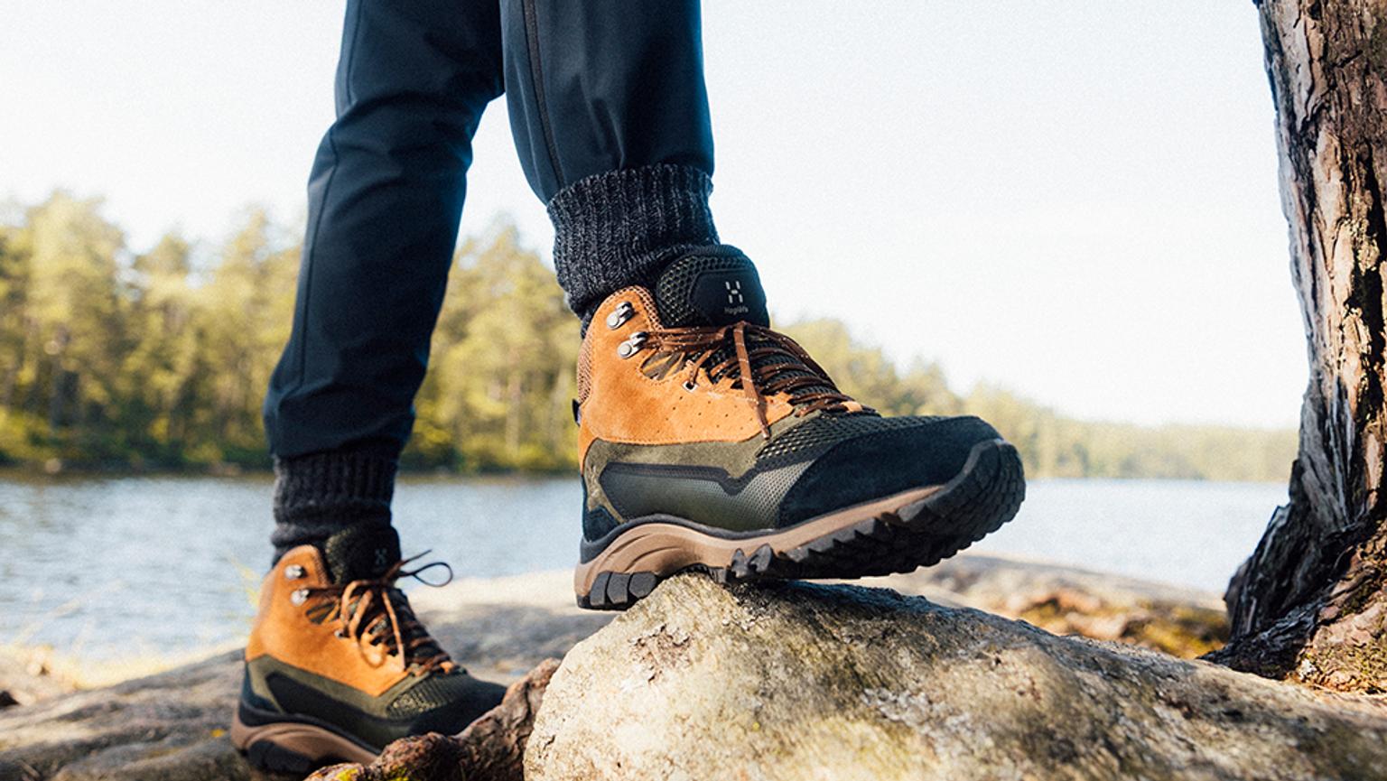 a person is standing on a rock wearing hiking boots .