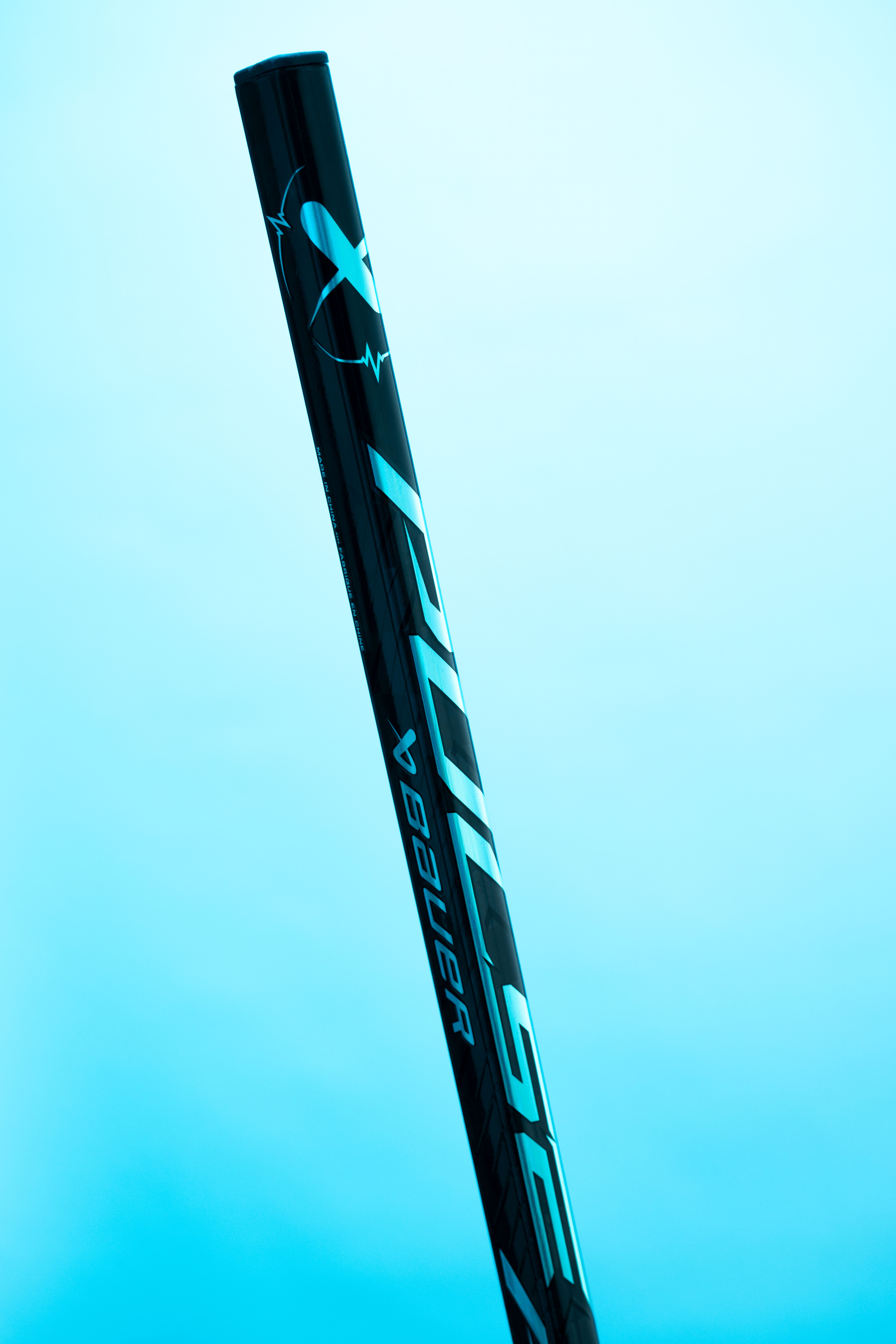 Black Bauer Hyperlite hockey stick with reflective blue branding against a light blue background.