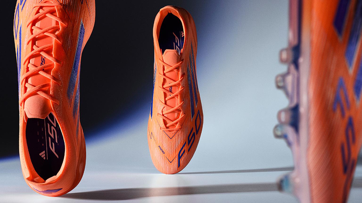 a pair of orange and blue soccer cleats are sitting on a table .