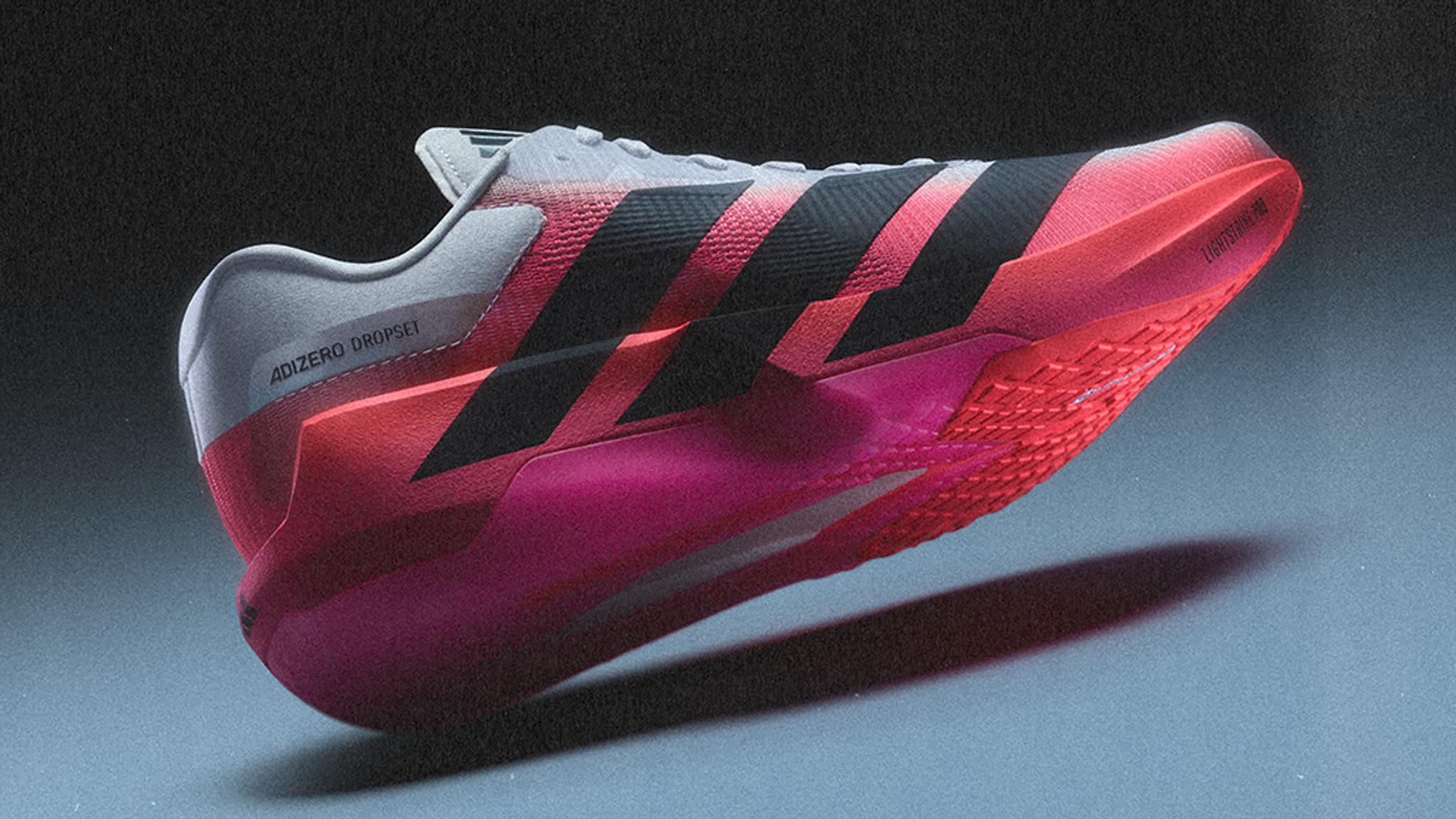 Adidas Adizero Dropsei running shoe in grey, pink, and red with black stripes, seen from the side.