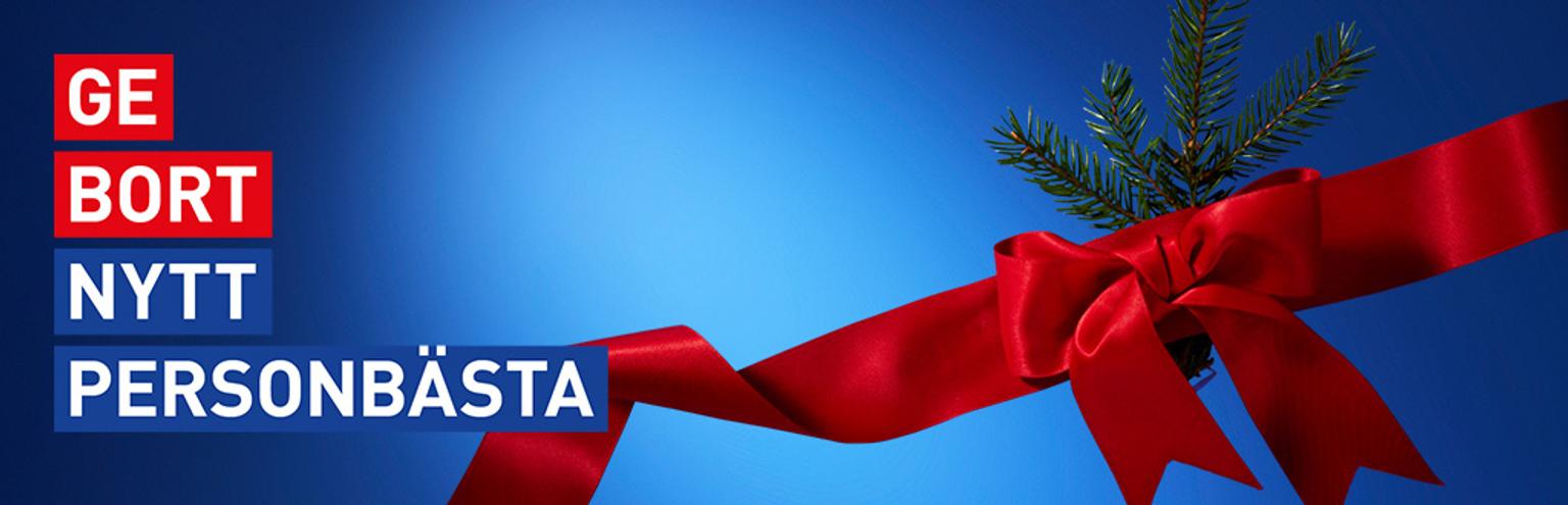 Red gift ribbon and fir sprig on a blue background, with the text "GE BORT NYTT PERSONBÄSTA".