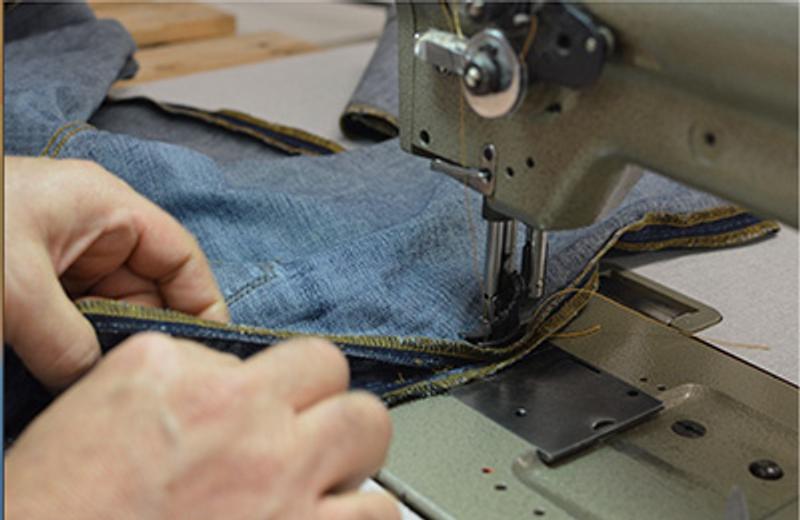 a person is using a sewing machine to sew a piece of fabric .