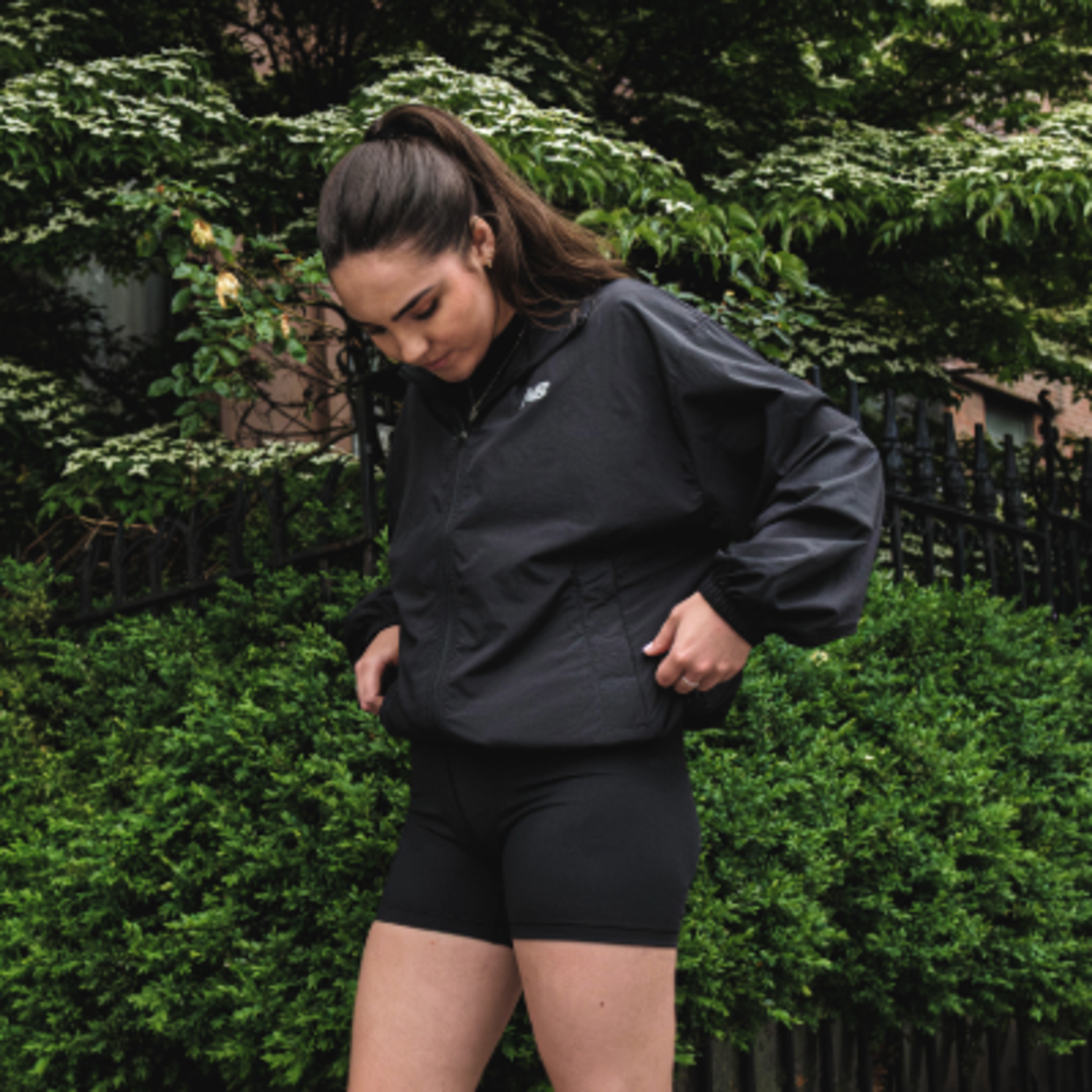 a woman wearing a black new balance jacket and shorts