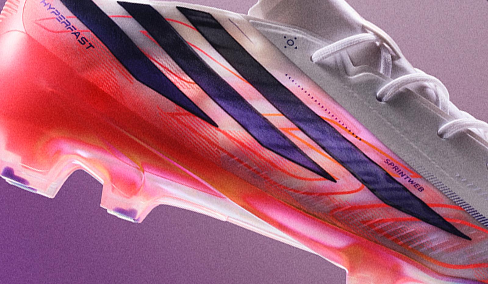 Close-up of a white soccer cleat with a red and pink translucent sole and purple stripes.