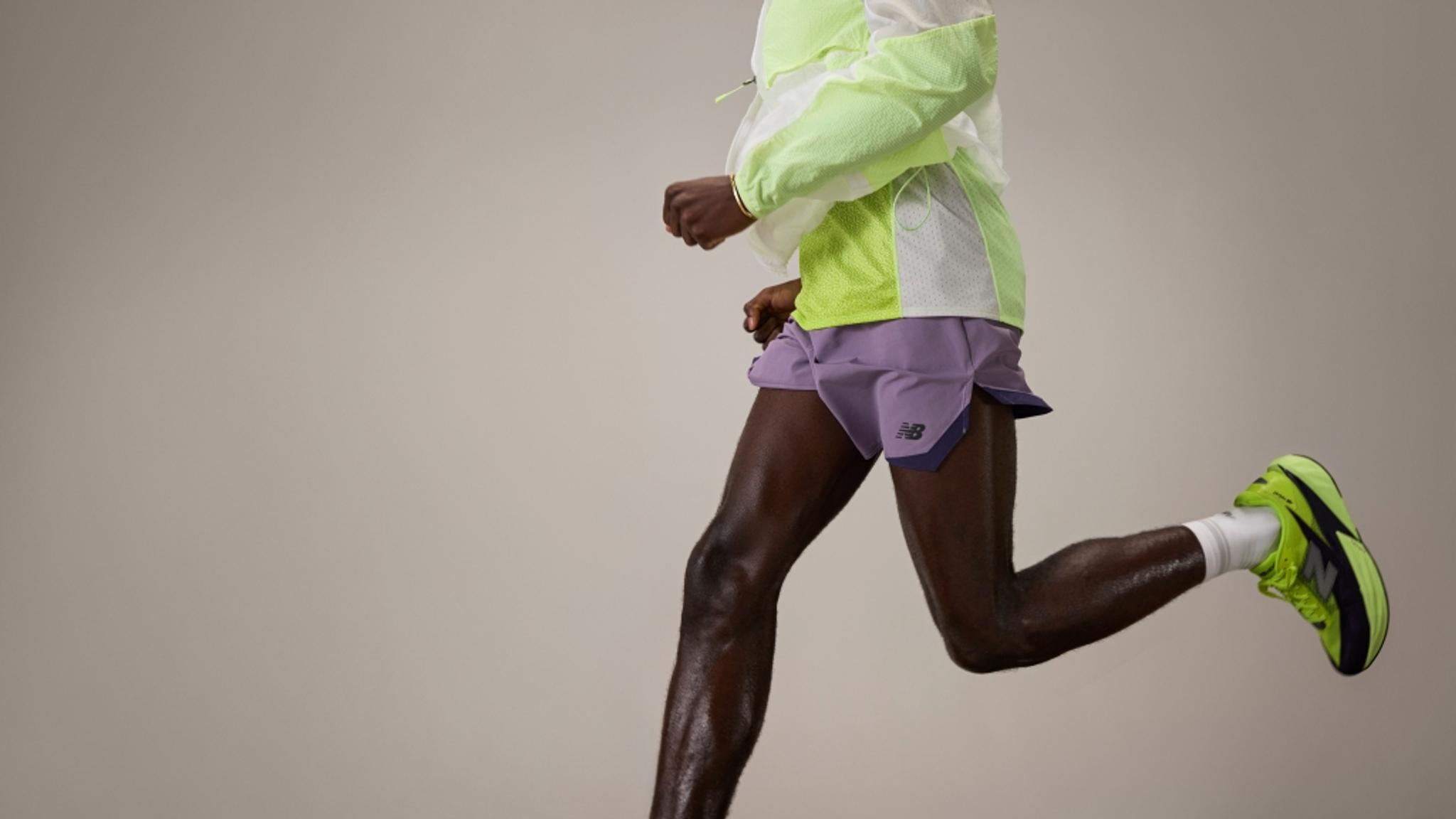 A runner in a neon green and white jacket, purple shorts, and neon green shoes, captured mid-stride.