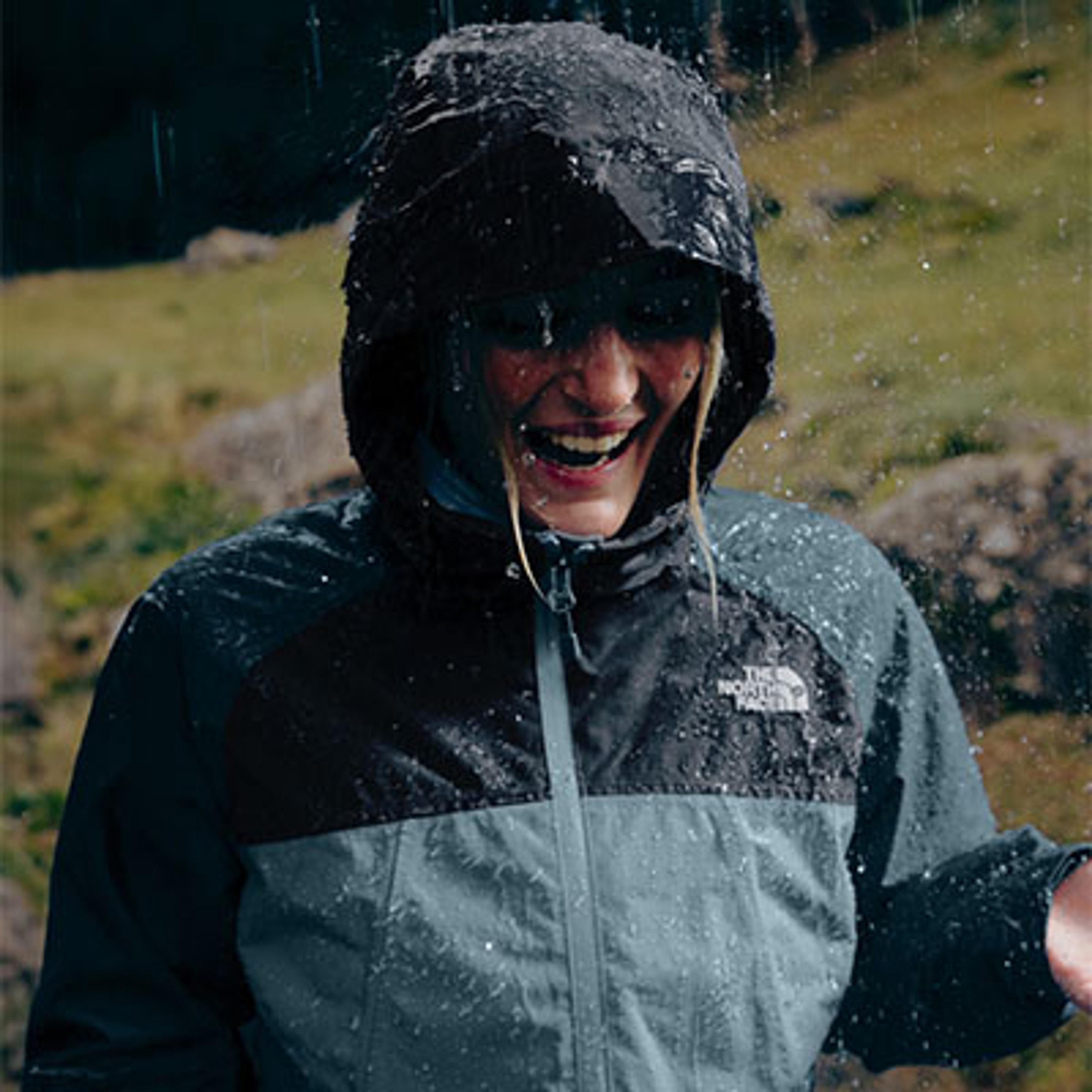 a woman wearing a north face jacket is standing in the rain .