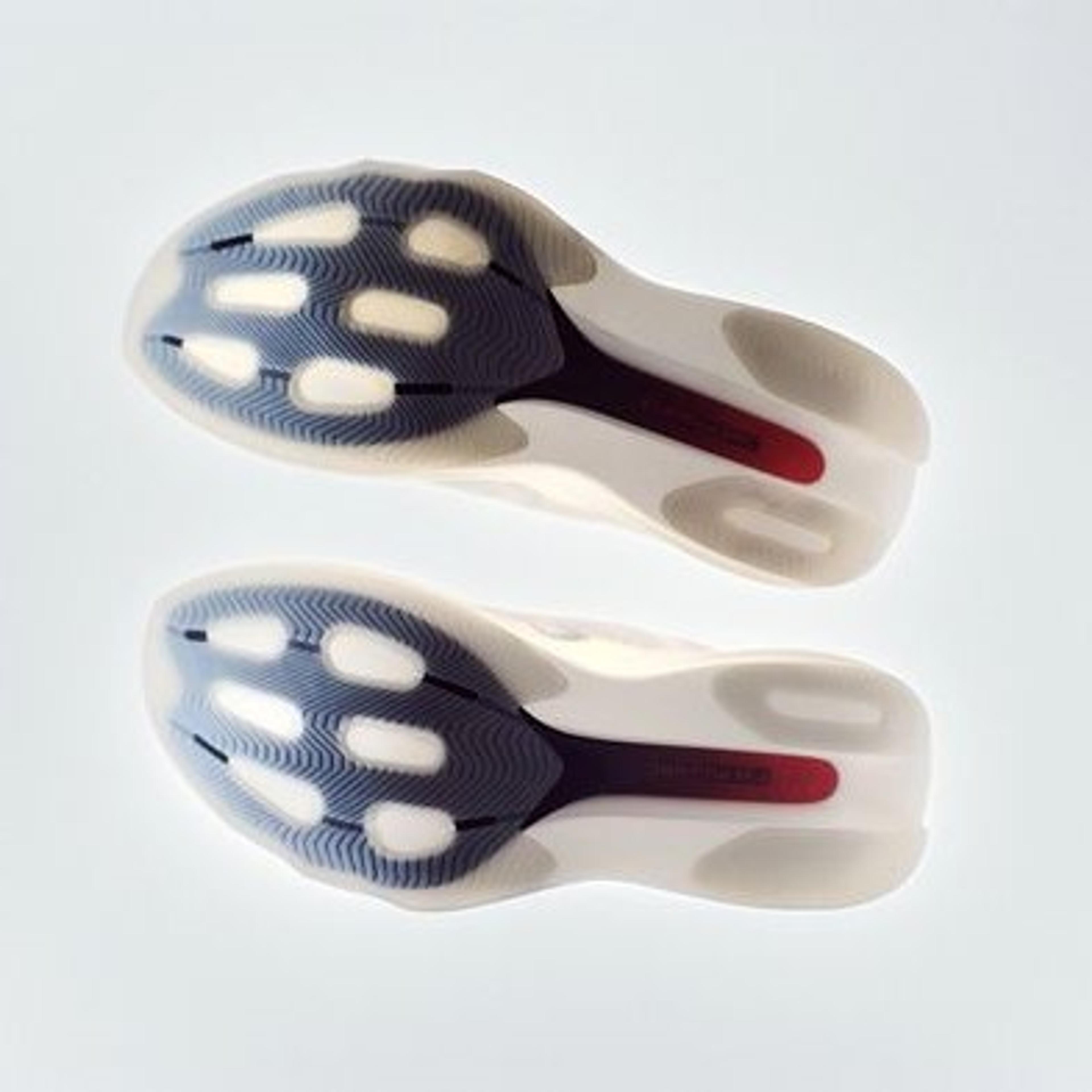 Two translucent shoe soles revealing a dark blue patterned base with white oval cushioning and a red heel accent.