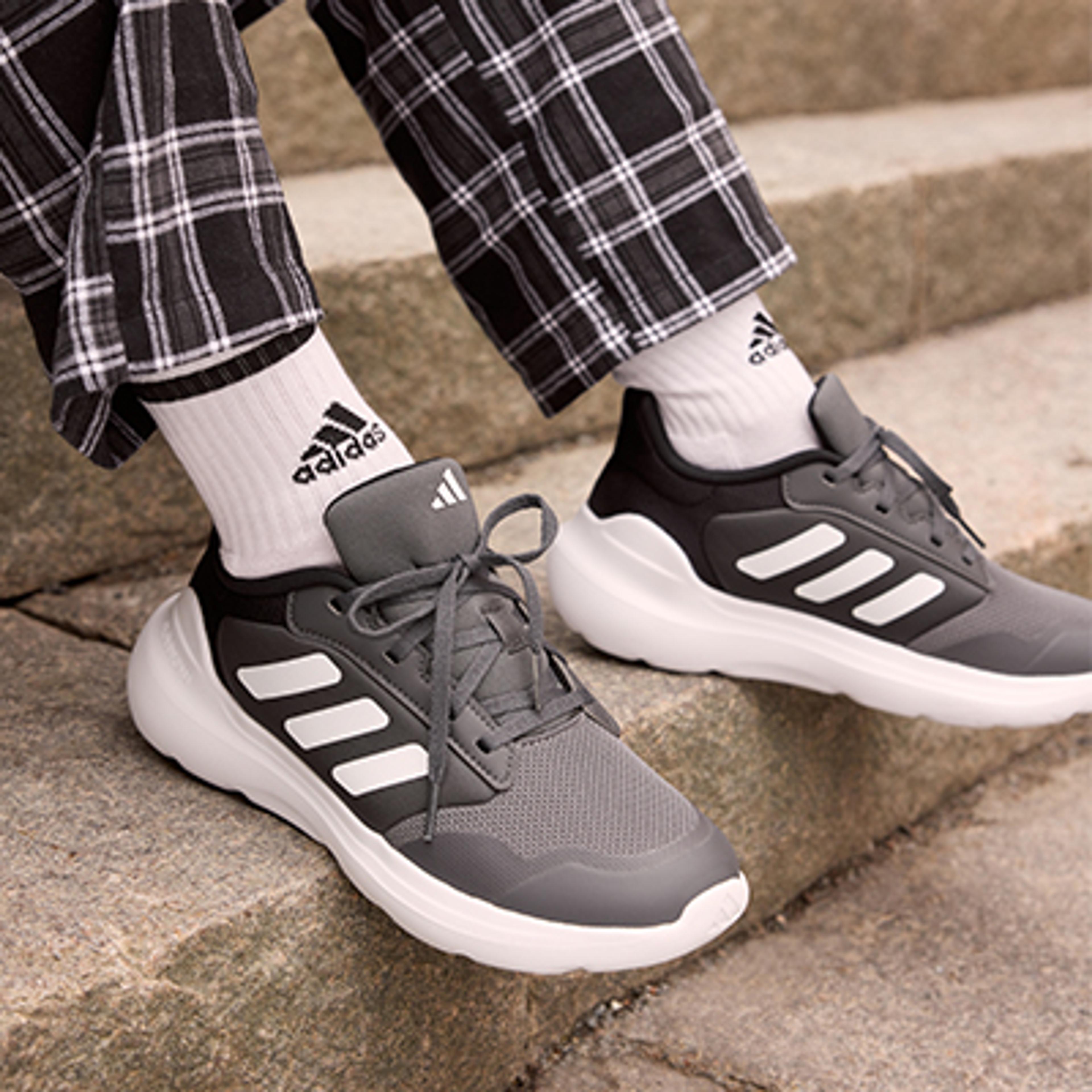 a person wearing a pair of adidas shoes is sitting on a set of stairs .