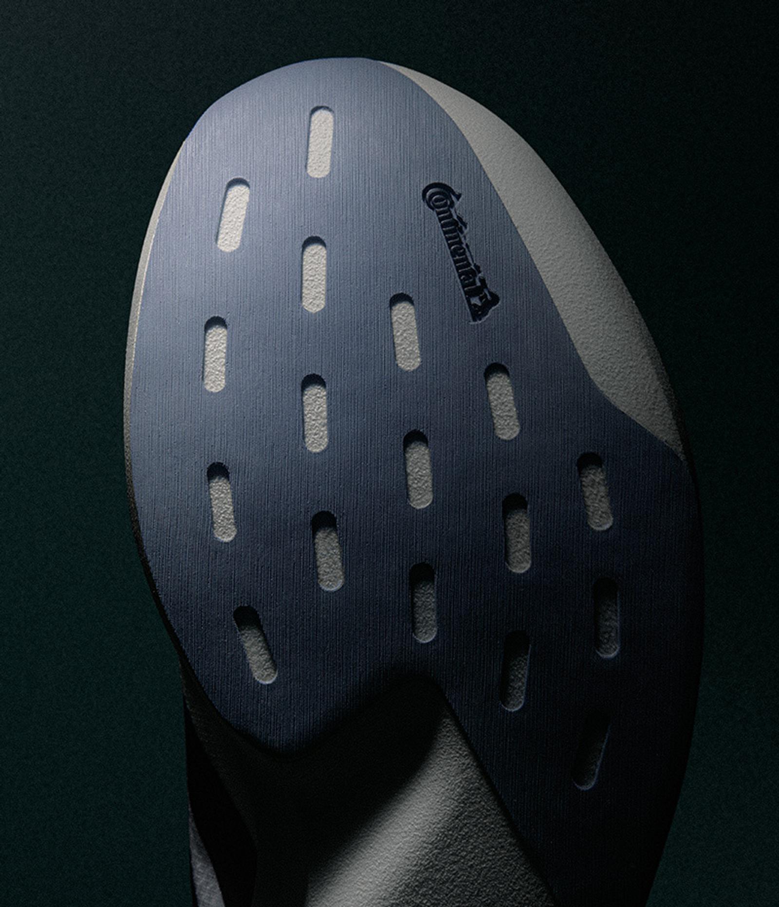 Close-up of a dark blue shoe sole with light grey oval tread patterns and a Continental logo.