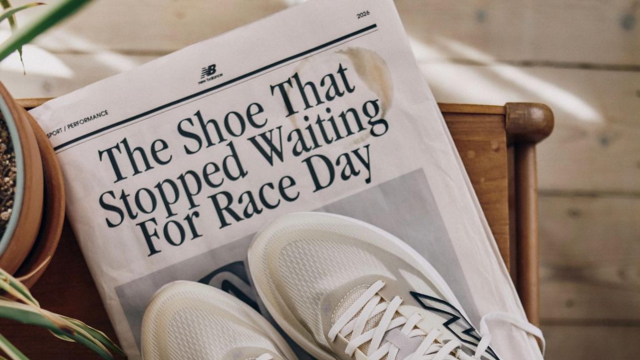 A pair of light-colored running shoes rests on a newspaper with the headline "The Shoe That Stopped Waiting For Race Day."