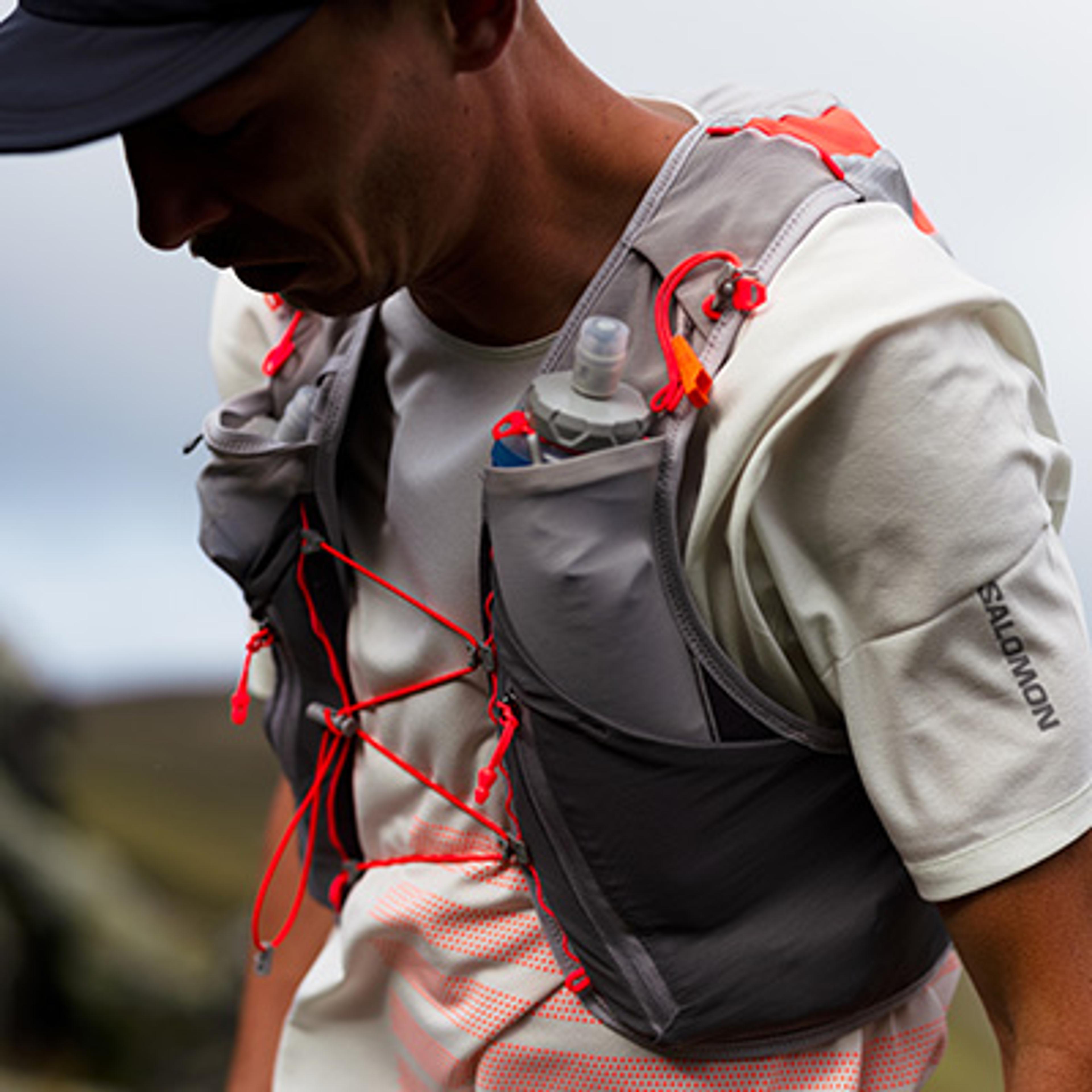 a man is wearing a backpack with a water bottle in it .