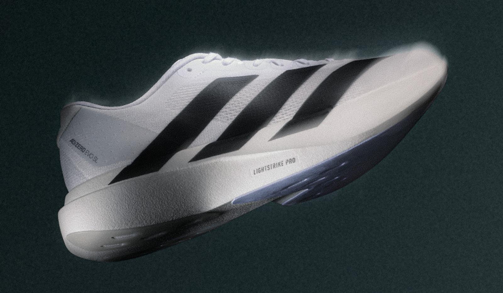 a person wearing a pair of white and black adidas shoes .