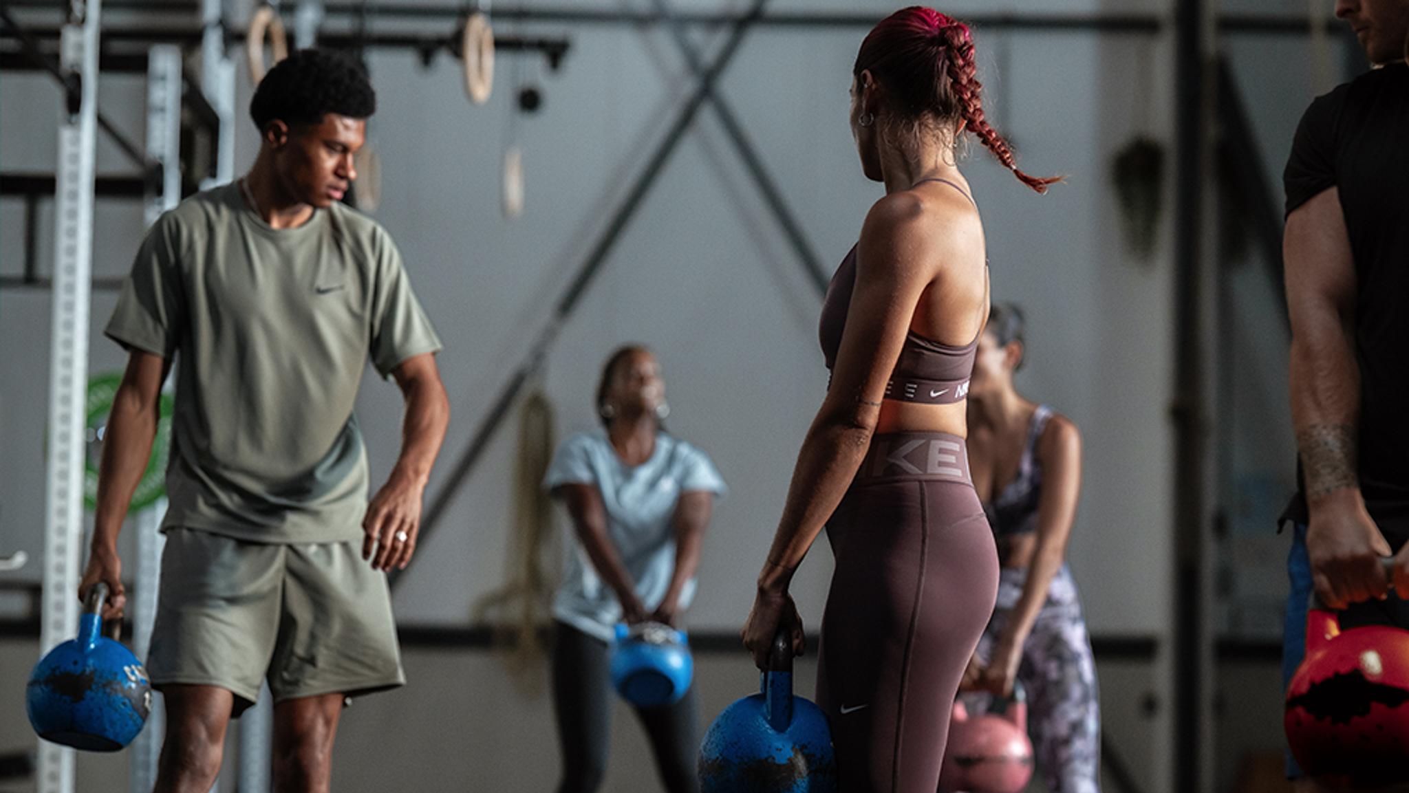 A group of people holding kettlebells during a workout in a gym.