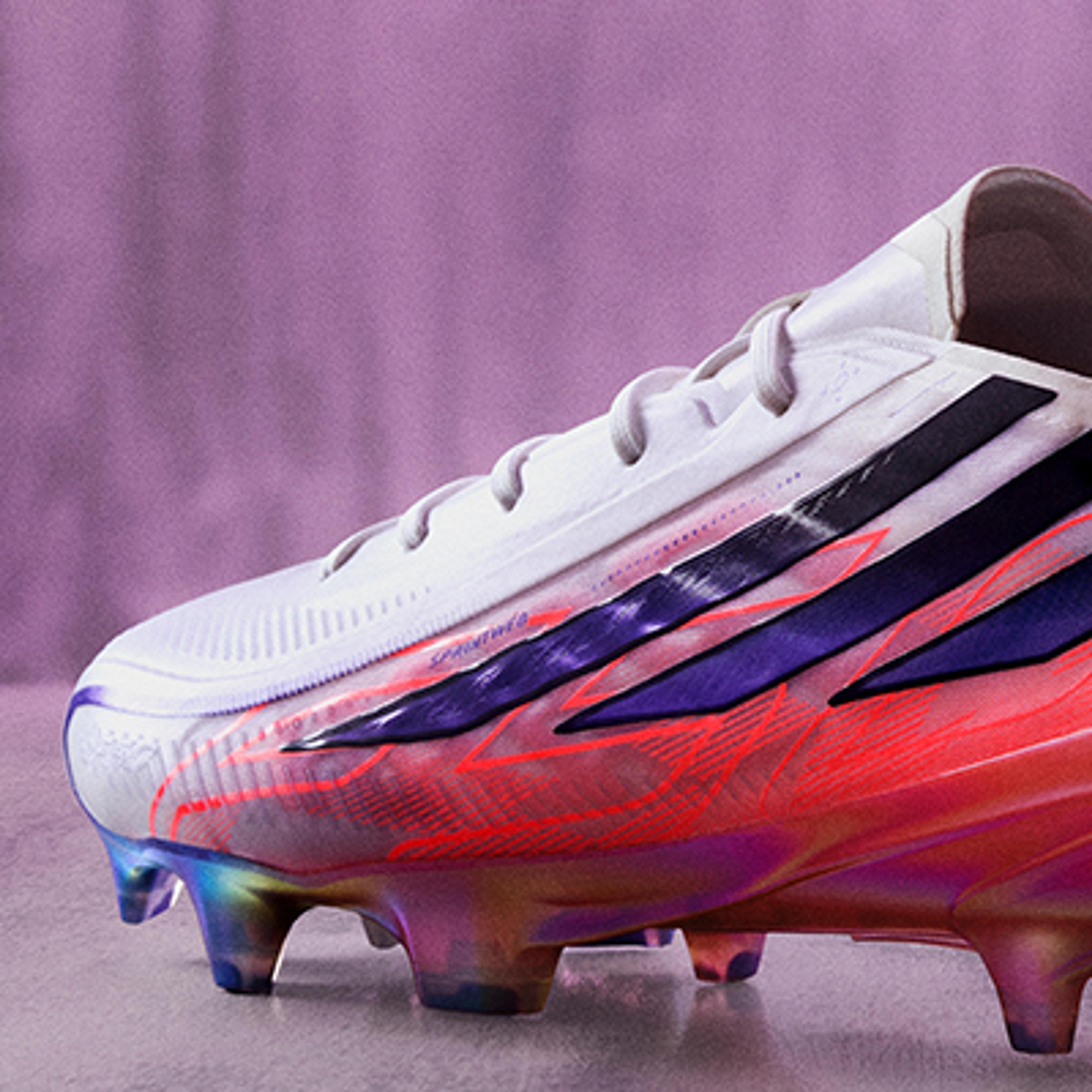White soccer cleat with black stripes, purple and orange accents, and an iridescent sole.