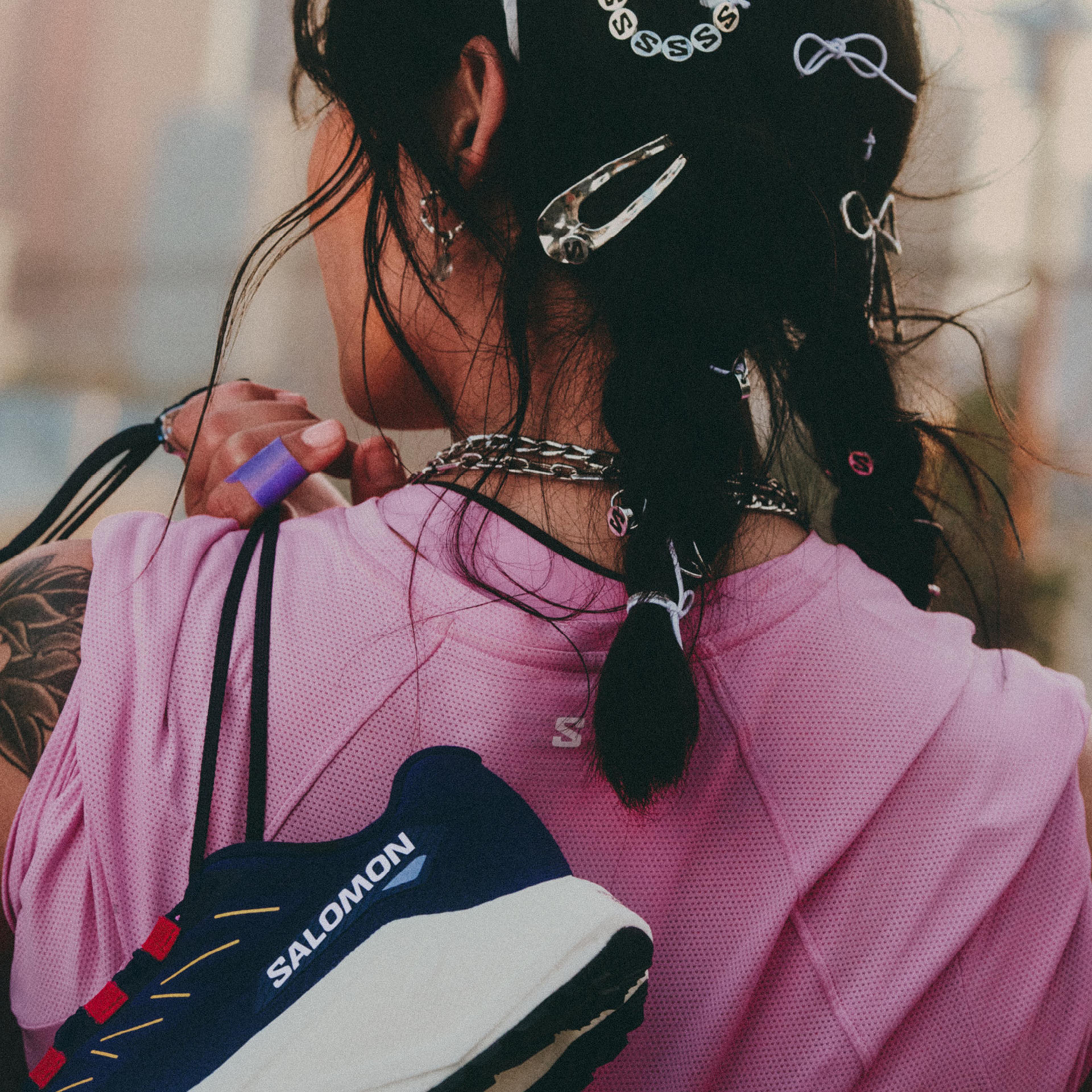 a woman is holding a pair of salomon shoes over her shoulder .
