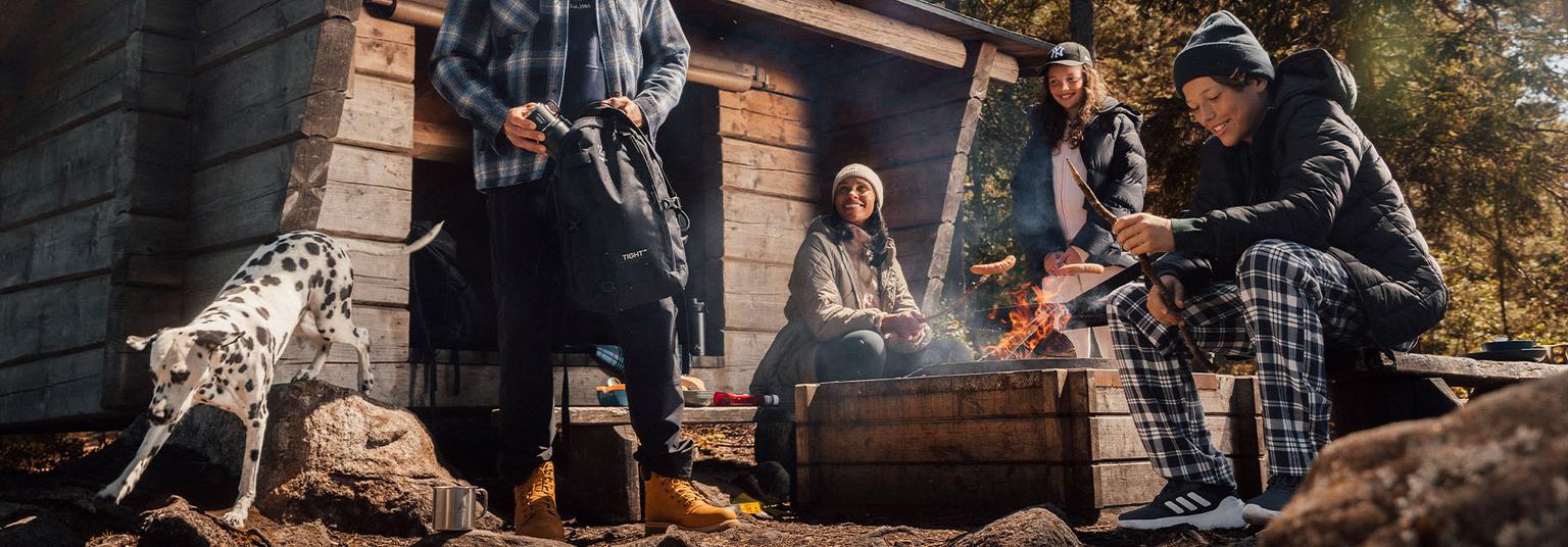 a group of people and a dalmatian dog are sitting around a campfire .