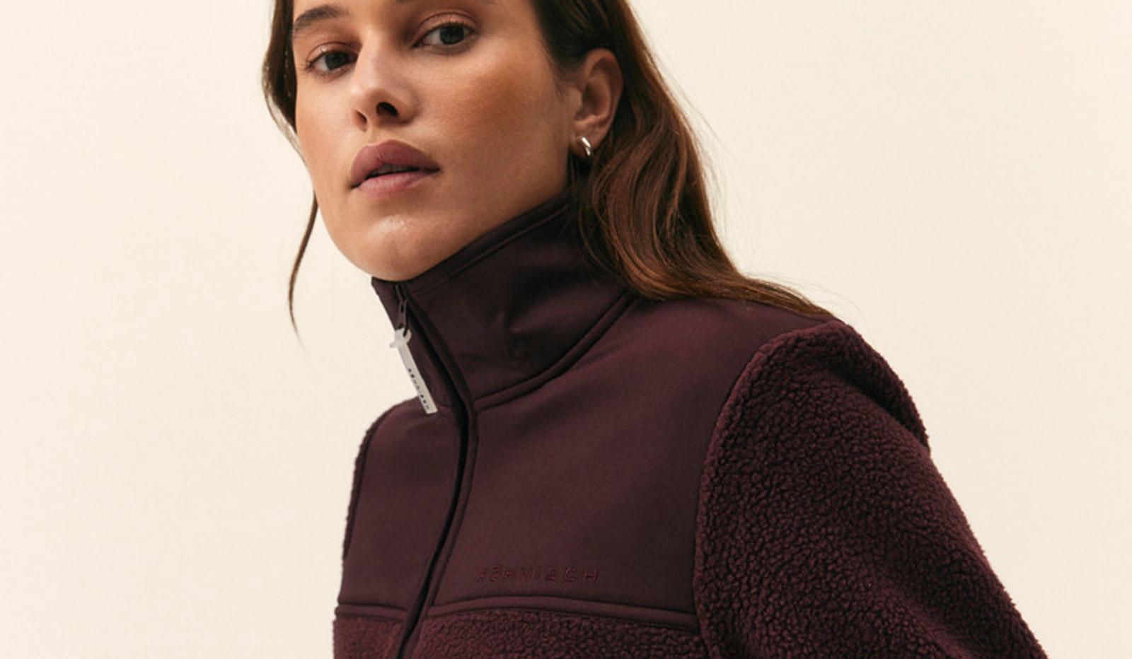 Woman in a burgundy high-collar zippered jacket with smooth and fleece sections.