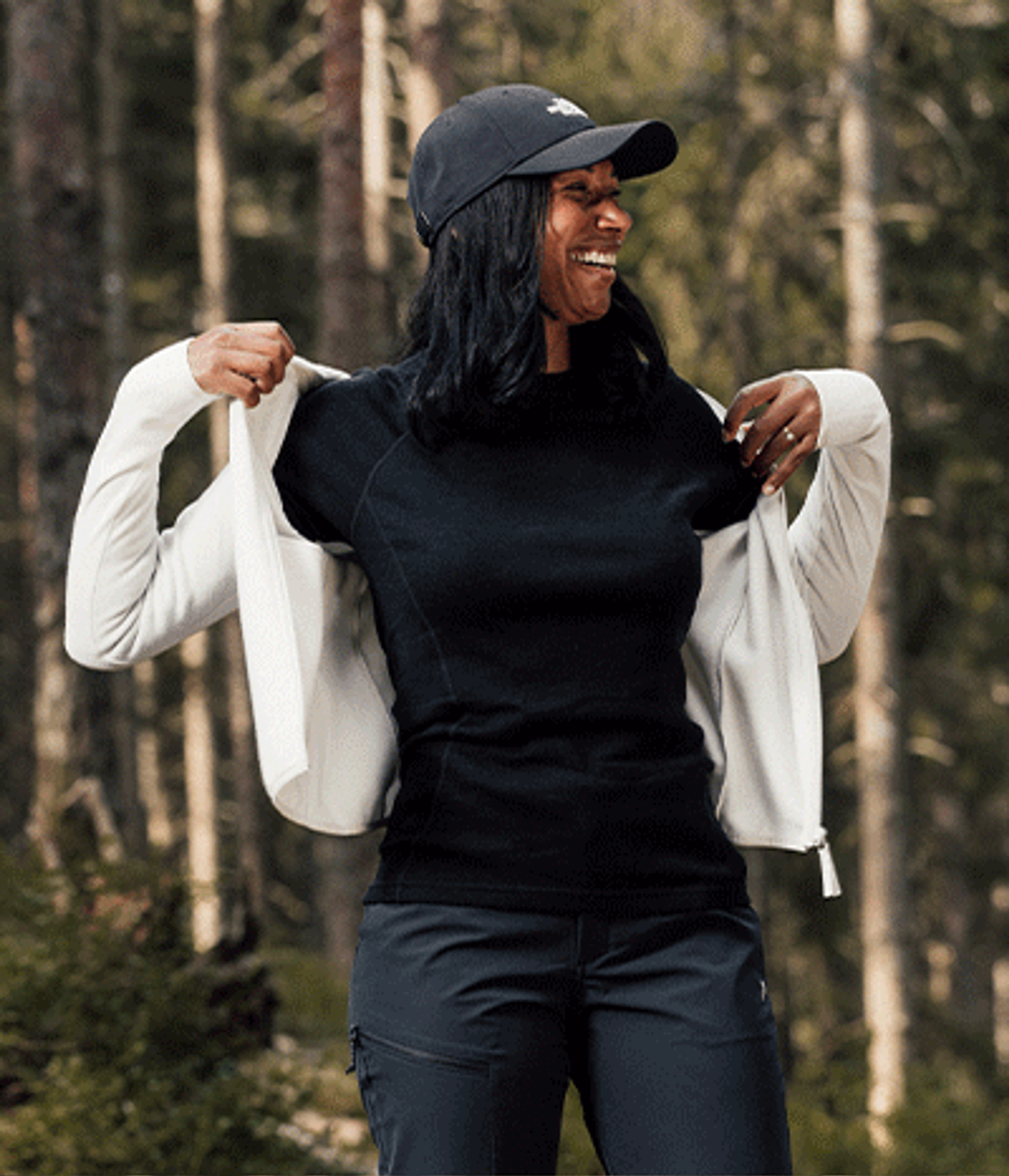 a woman wearing a black hat and a white jacket is smiling