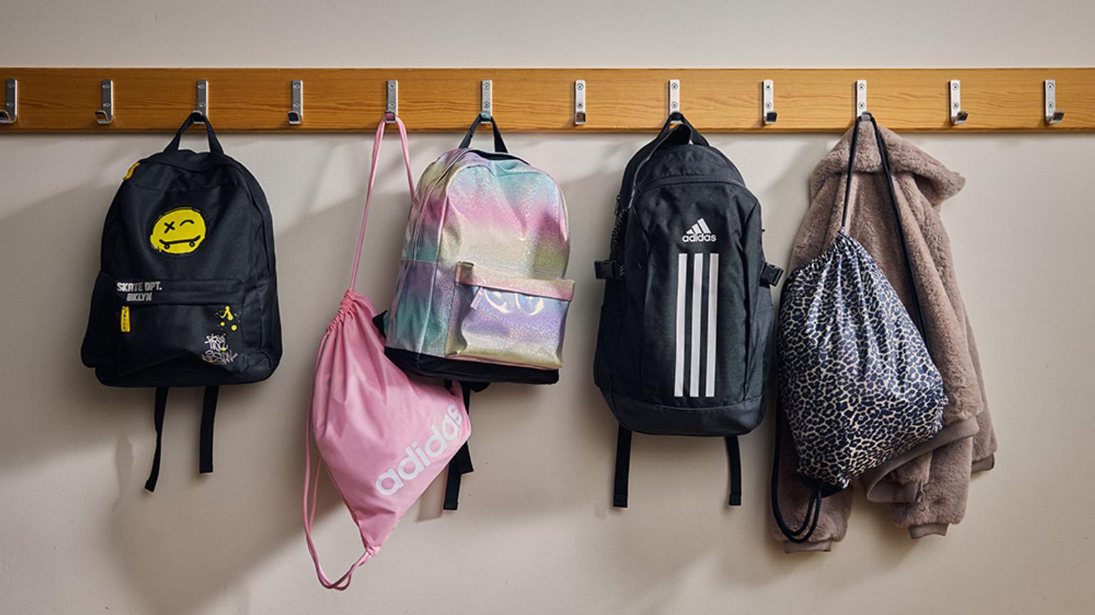 a row of backpacks hanging on hooks on a wall .