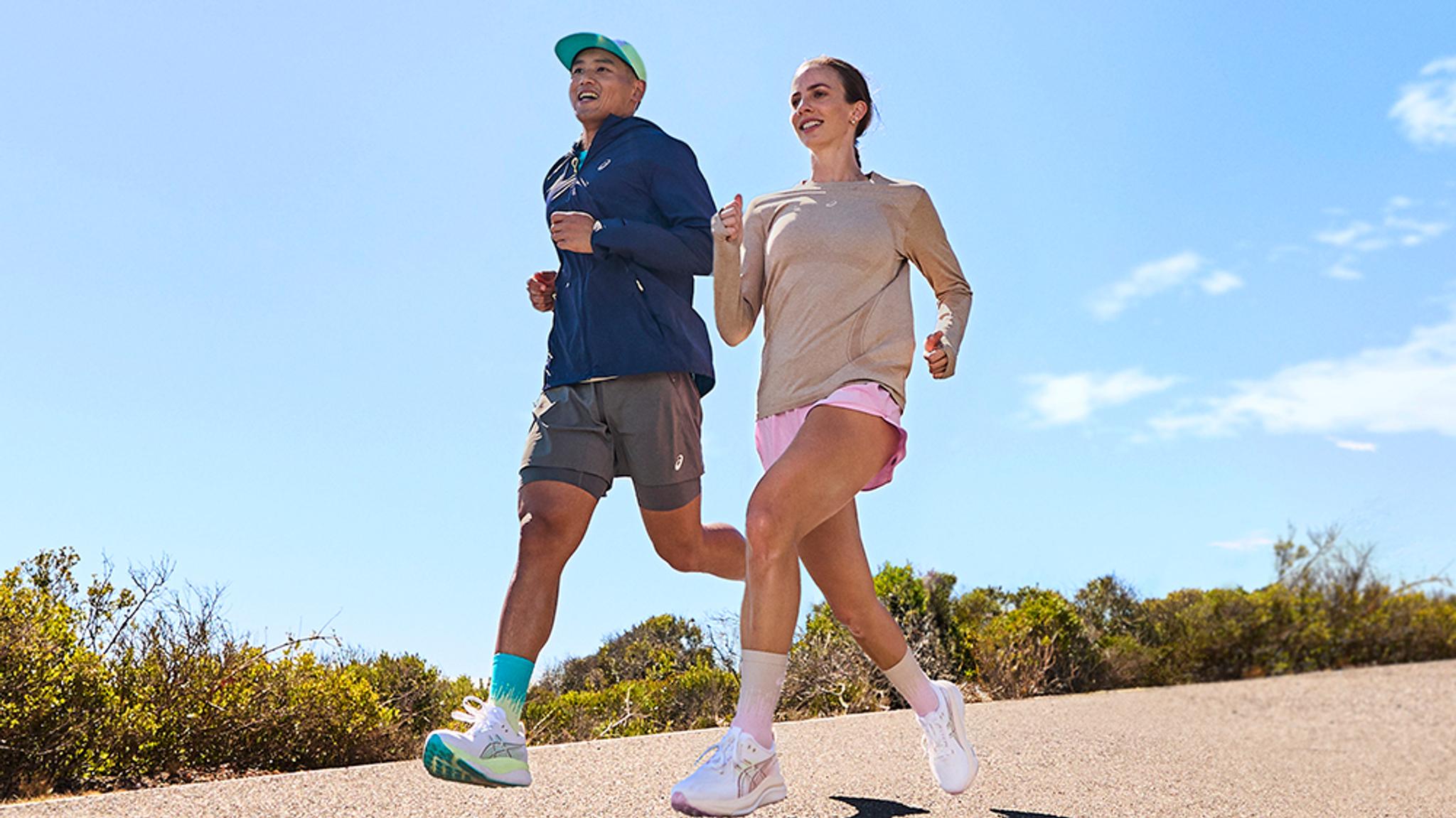 A man and woman running together outdoors on a sunny day.