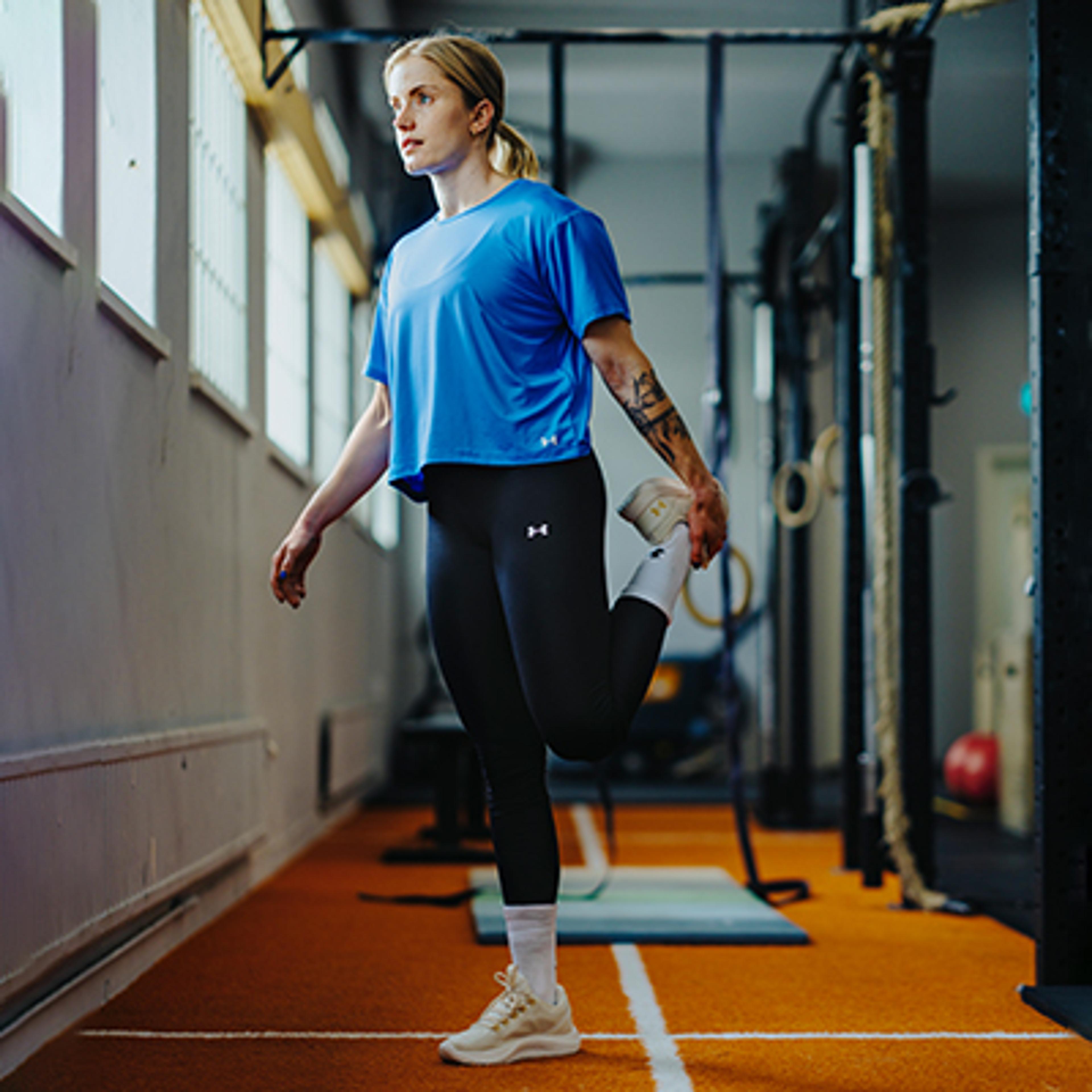 a woman is stretching her legs in a gym .