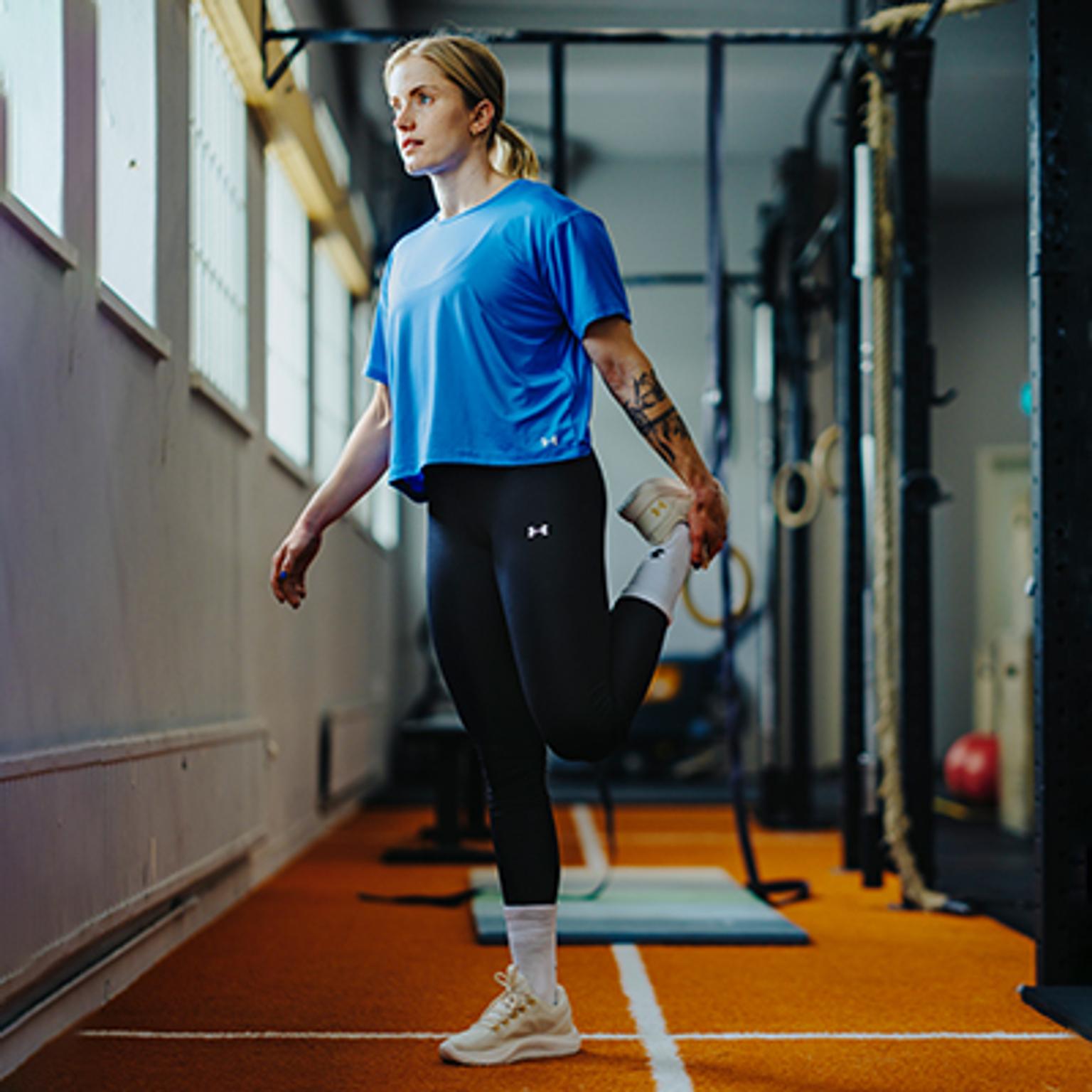 a woman is stretching her legs in a gym .