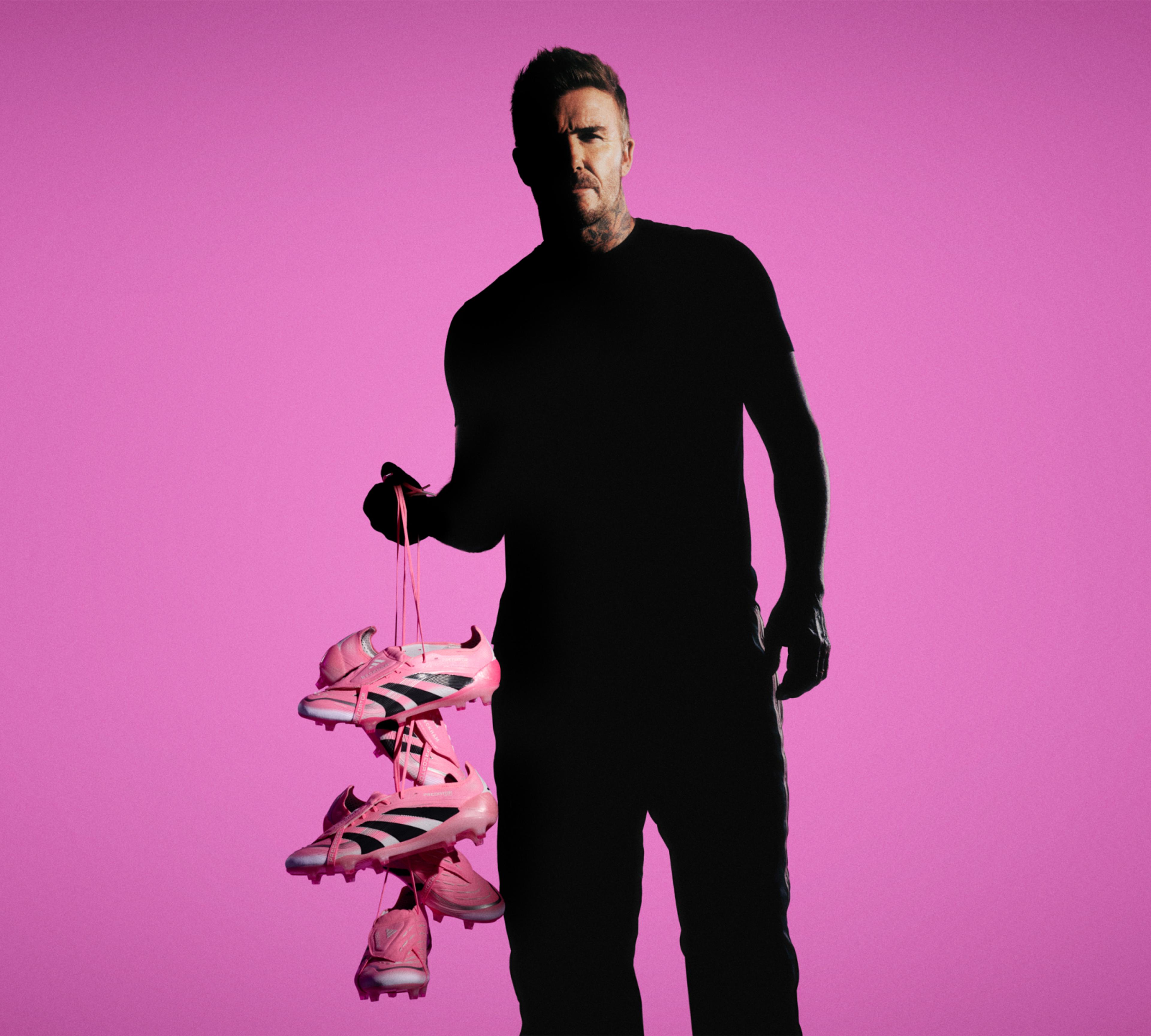 a man is holding a stack of pink soccer cleats .