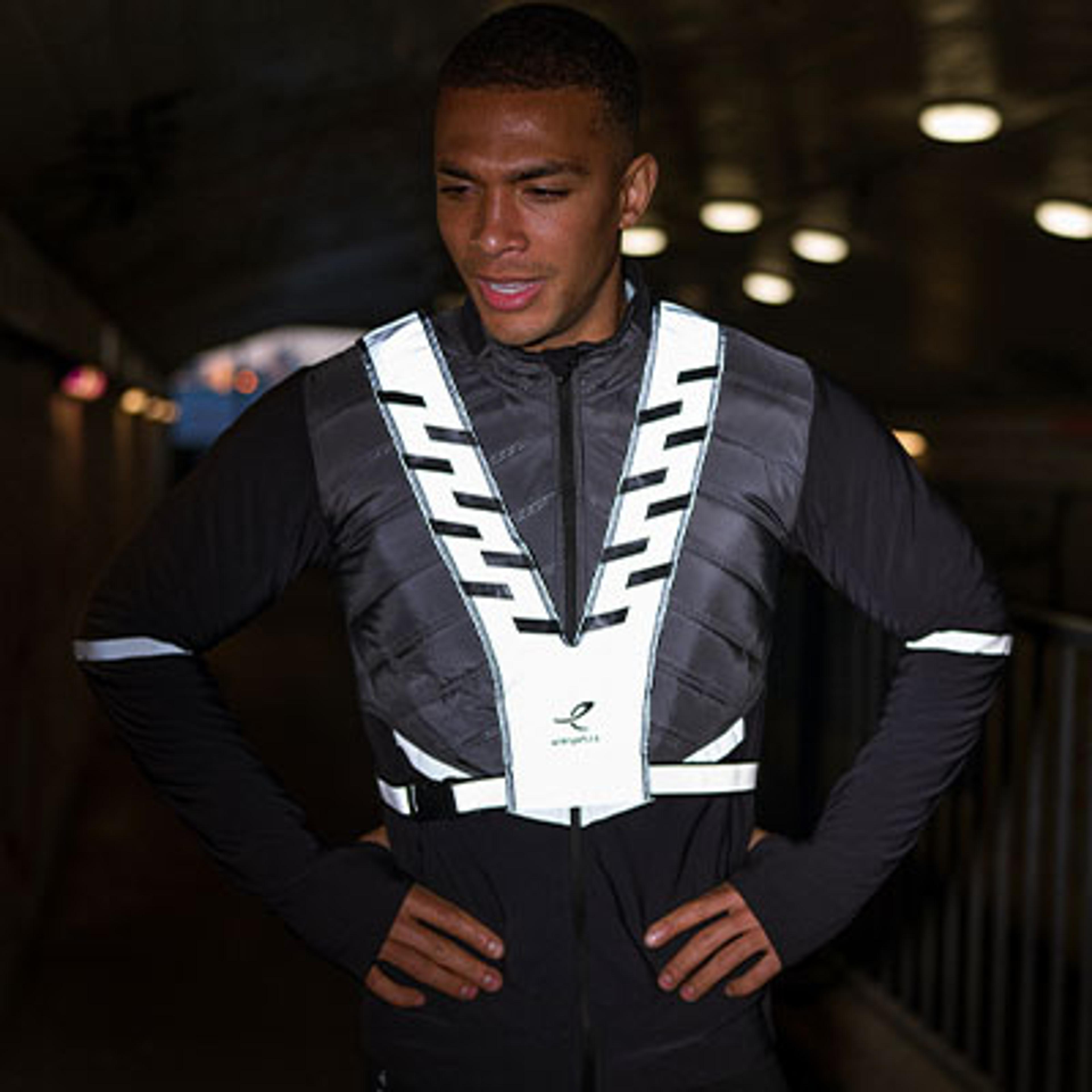 a man wearing a reflective vest is standing with his hands on his hips .