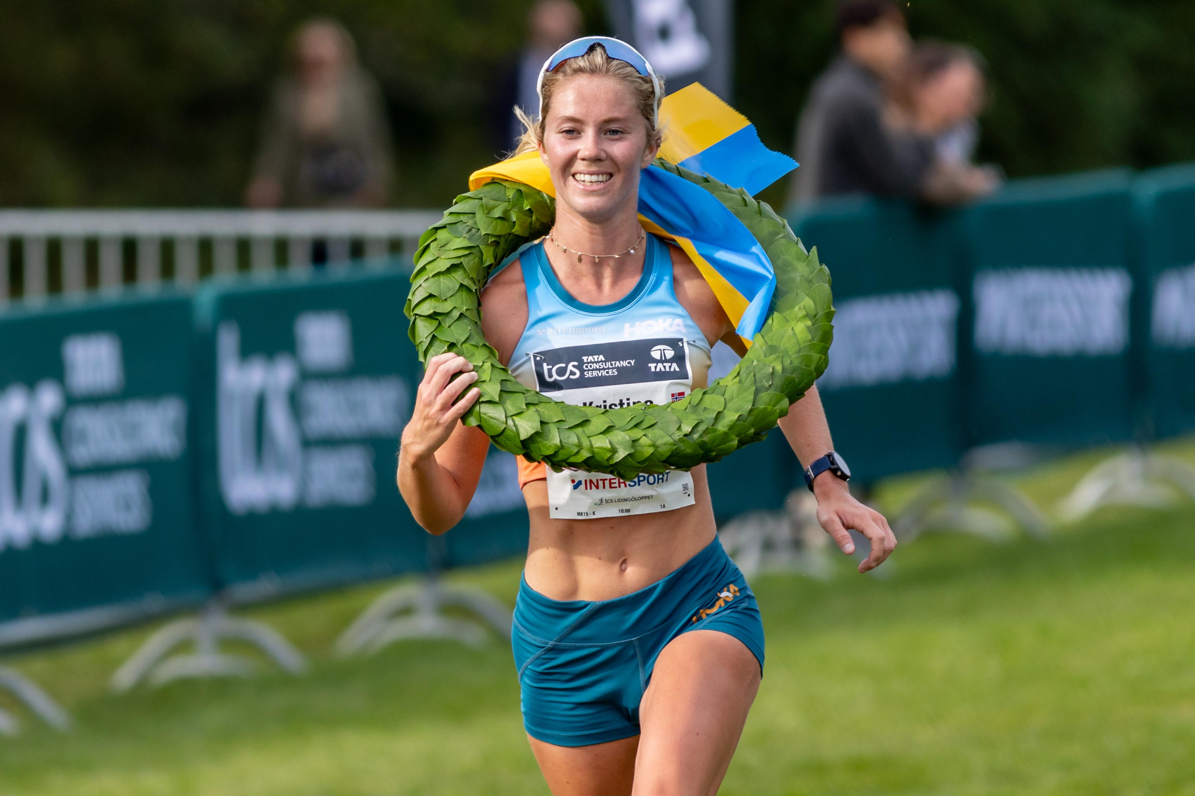 a woman is running with a wreath around her neck .