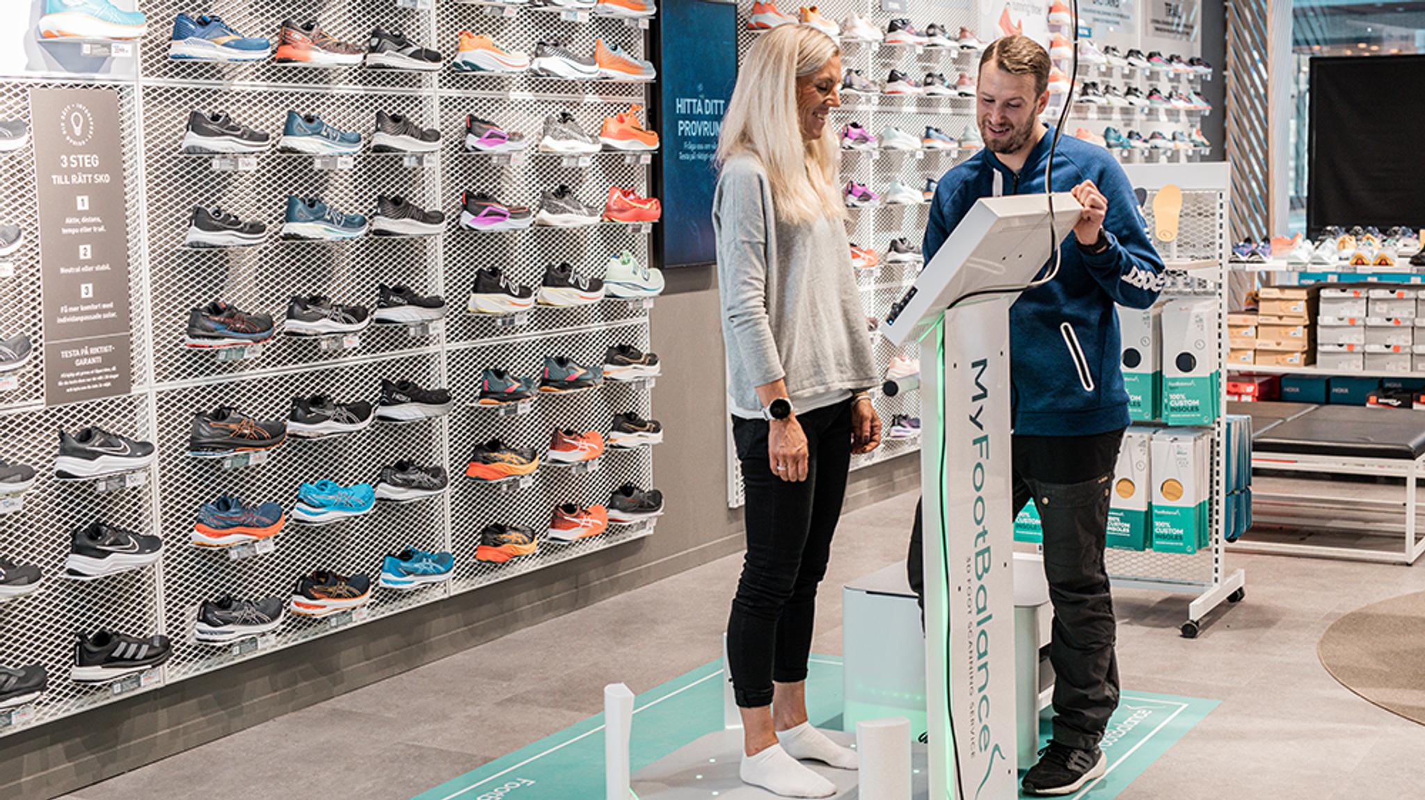 a man and a woman are standing next to each other in a shoe store .