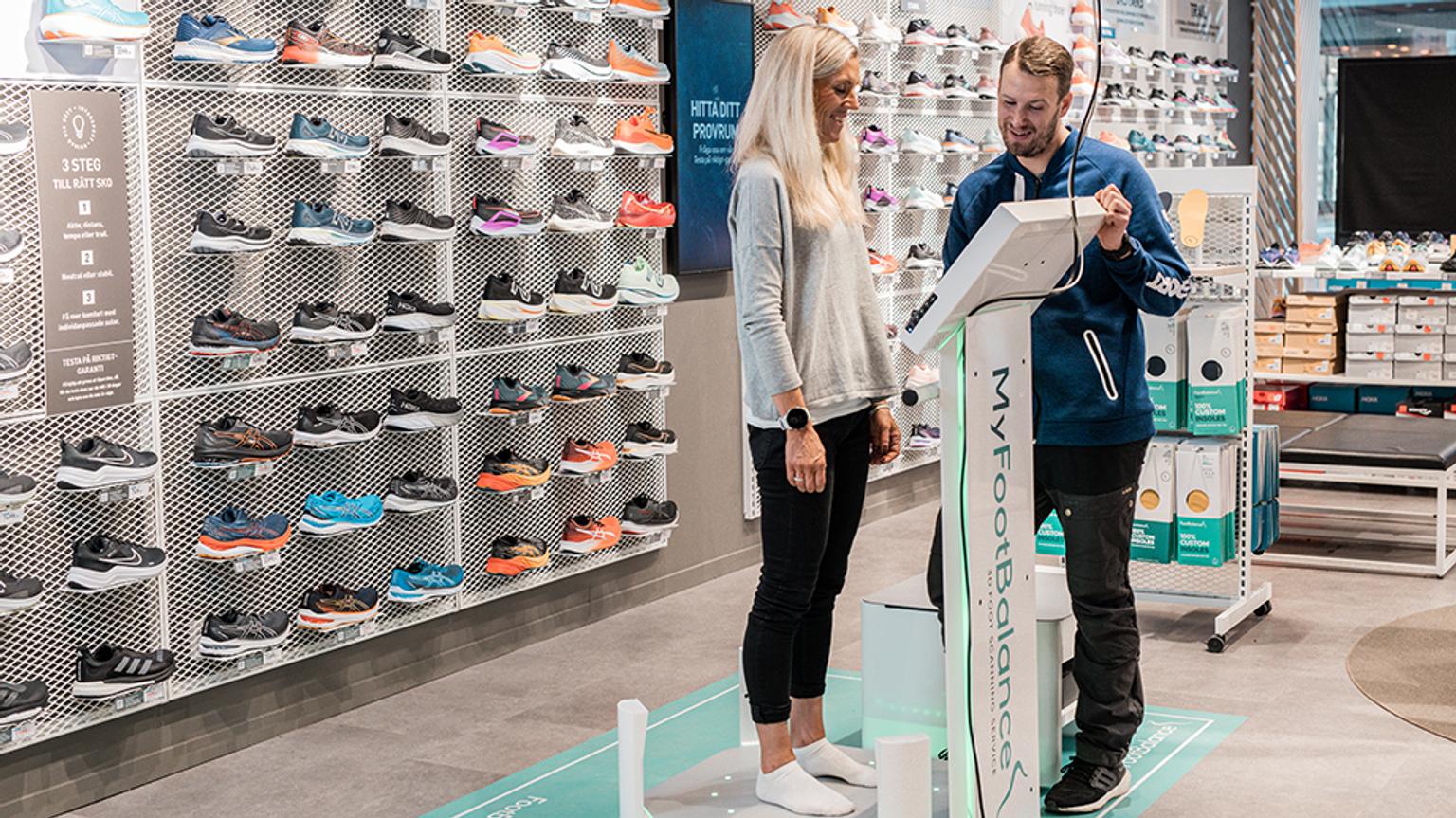 a man and a woman are standing next to each other in a shoe store .