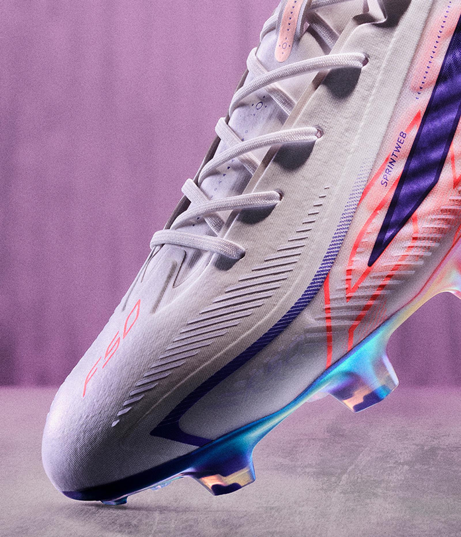 Close-up of a white and purple soccer cleat with an iridescent blue sole, featuring F50 and SPRINTWEB text.