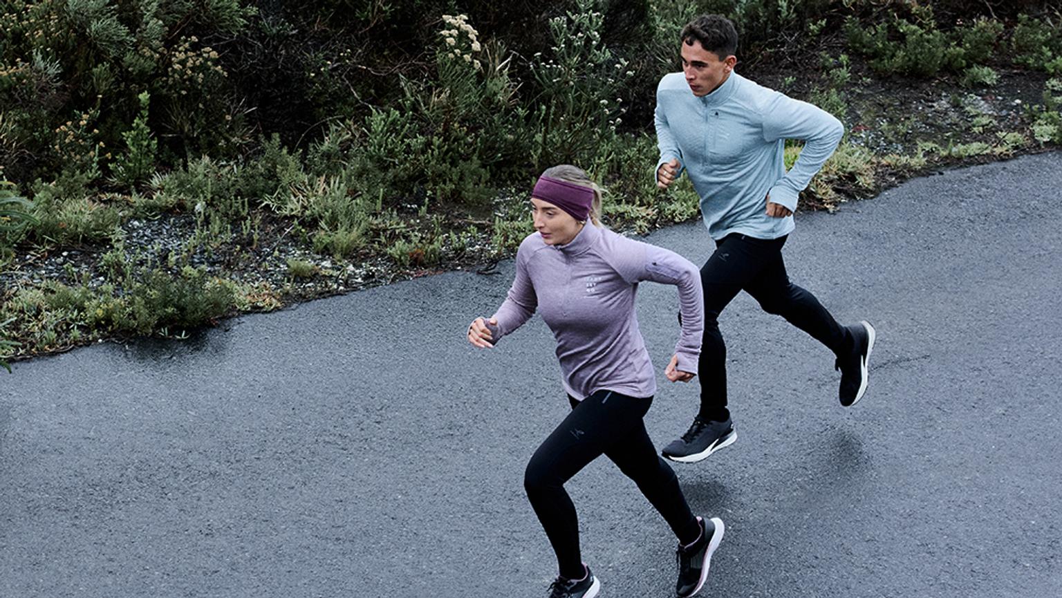 a man and a woman are running down a road .