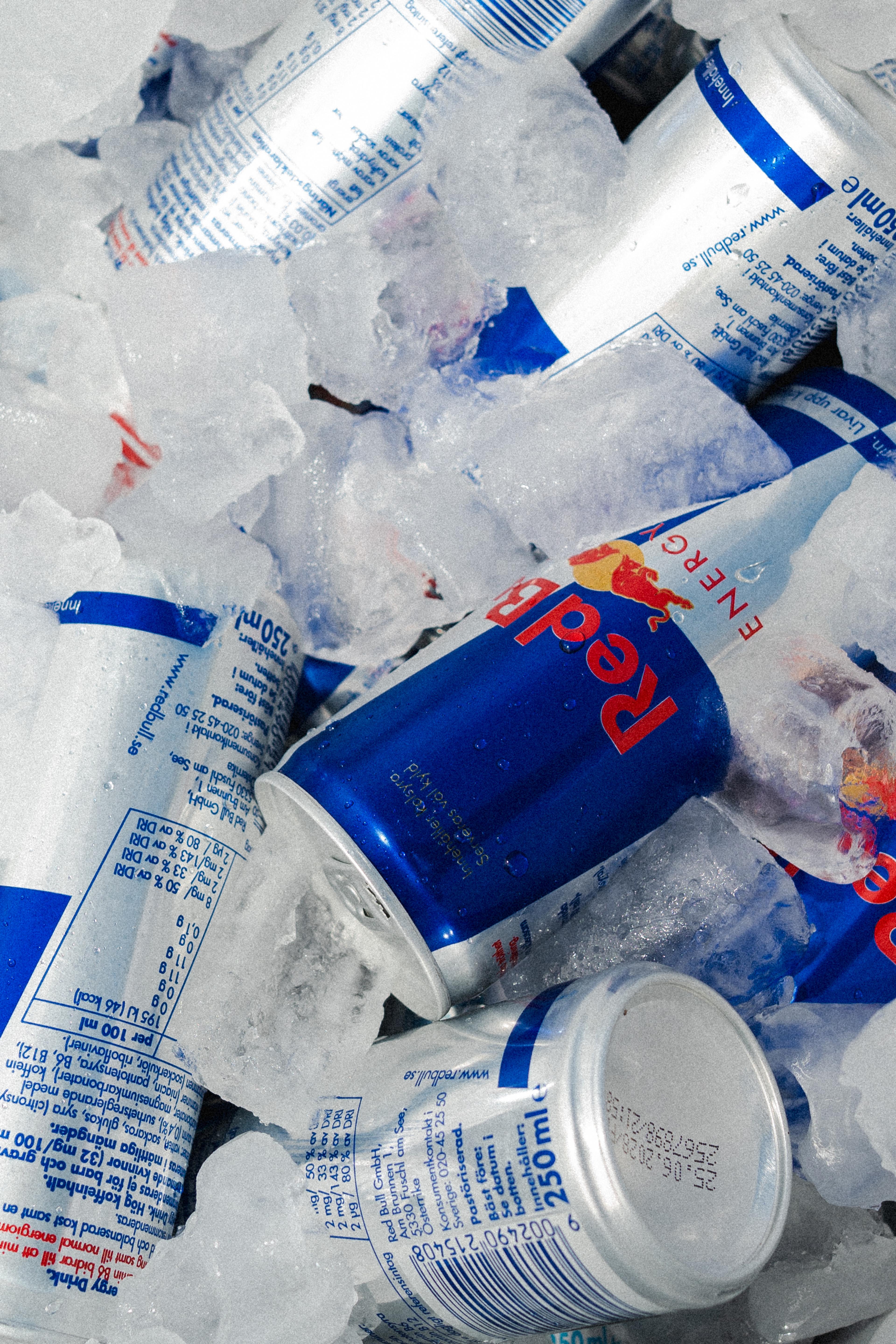 Multiple Red Bull cans chilling in ice.