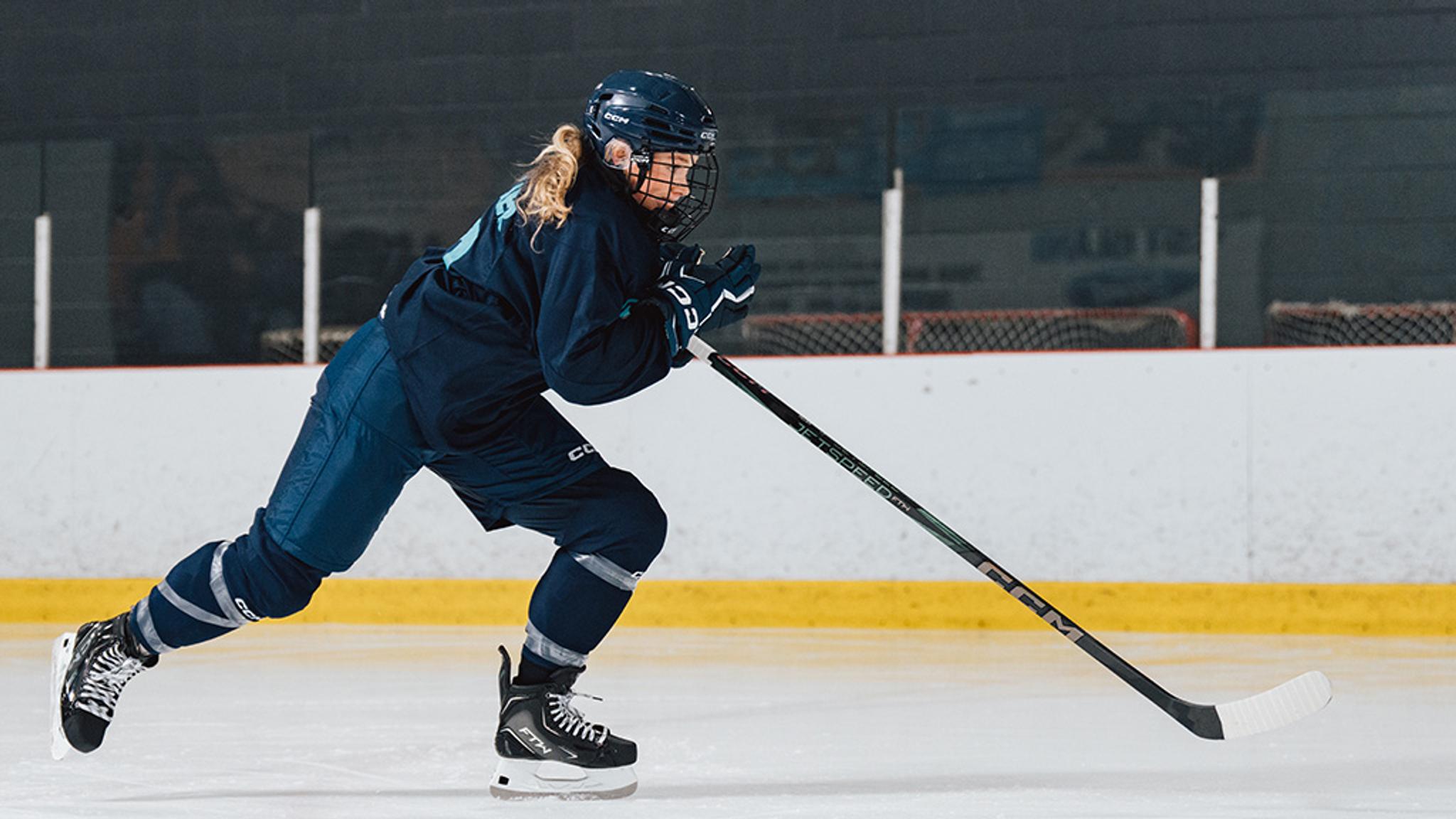 a woman is playing ice hockey on a rink .