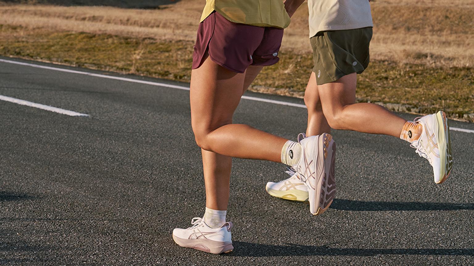 a couple of people are running down a road .
