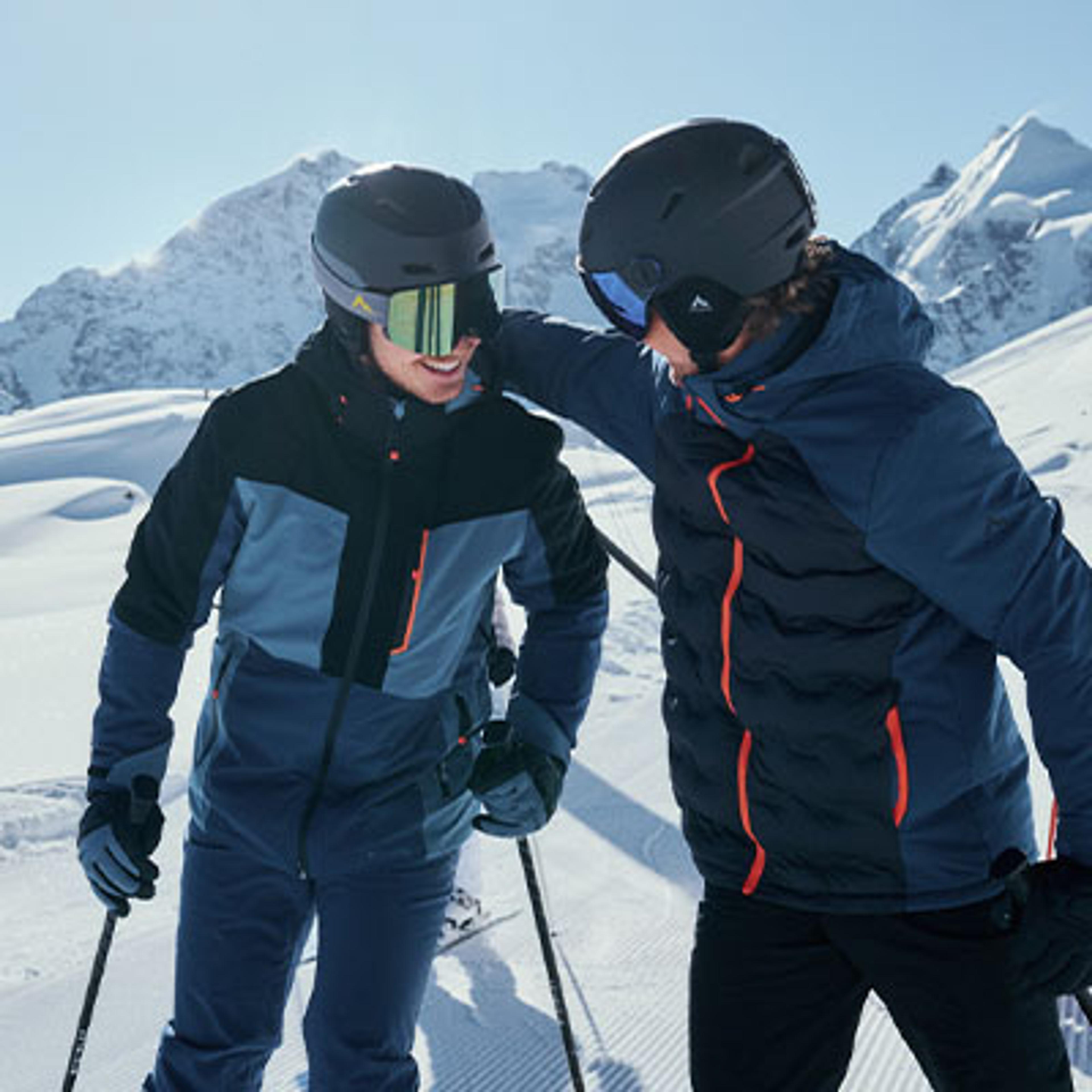 two men wearing helmets and goggles are standing next to each other in the snow .