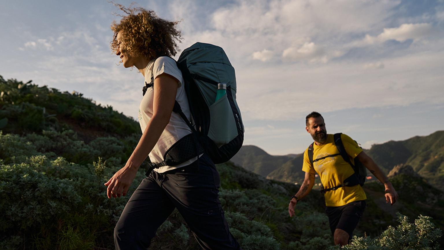 a man and a woman are hiking in the mountains .