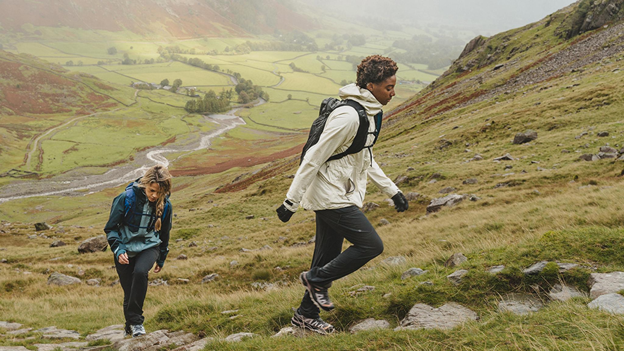 a man and a woman are hiking up a hill .