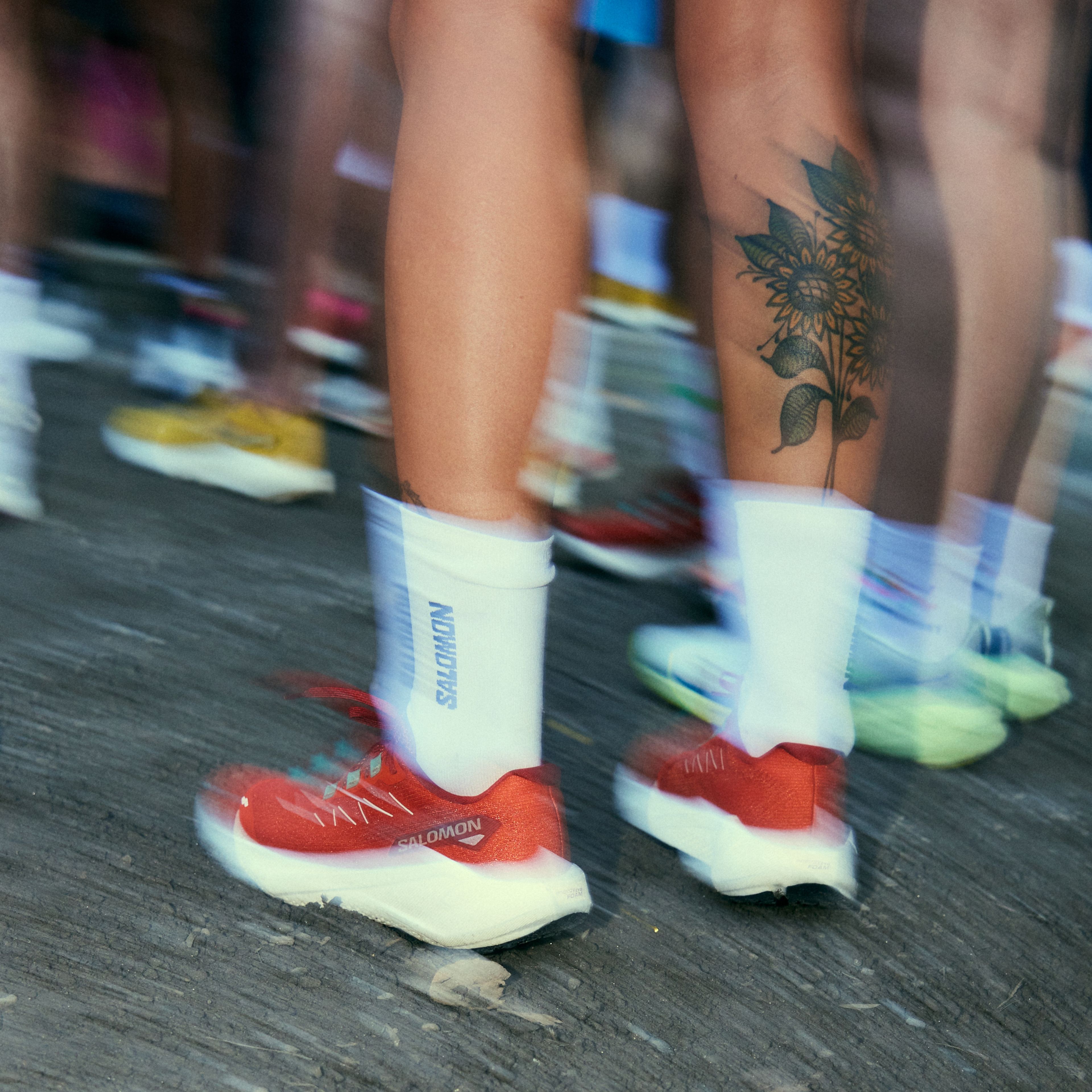 a person with a tattoo on their leg is wearing a pair of red and white sneakers .
