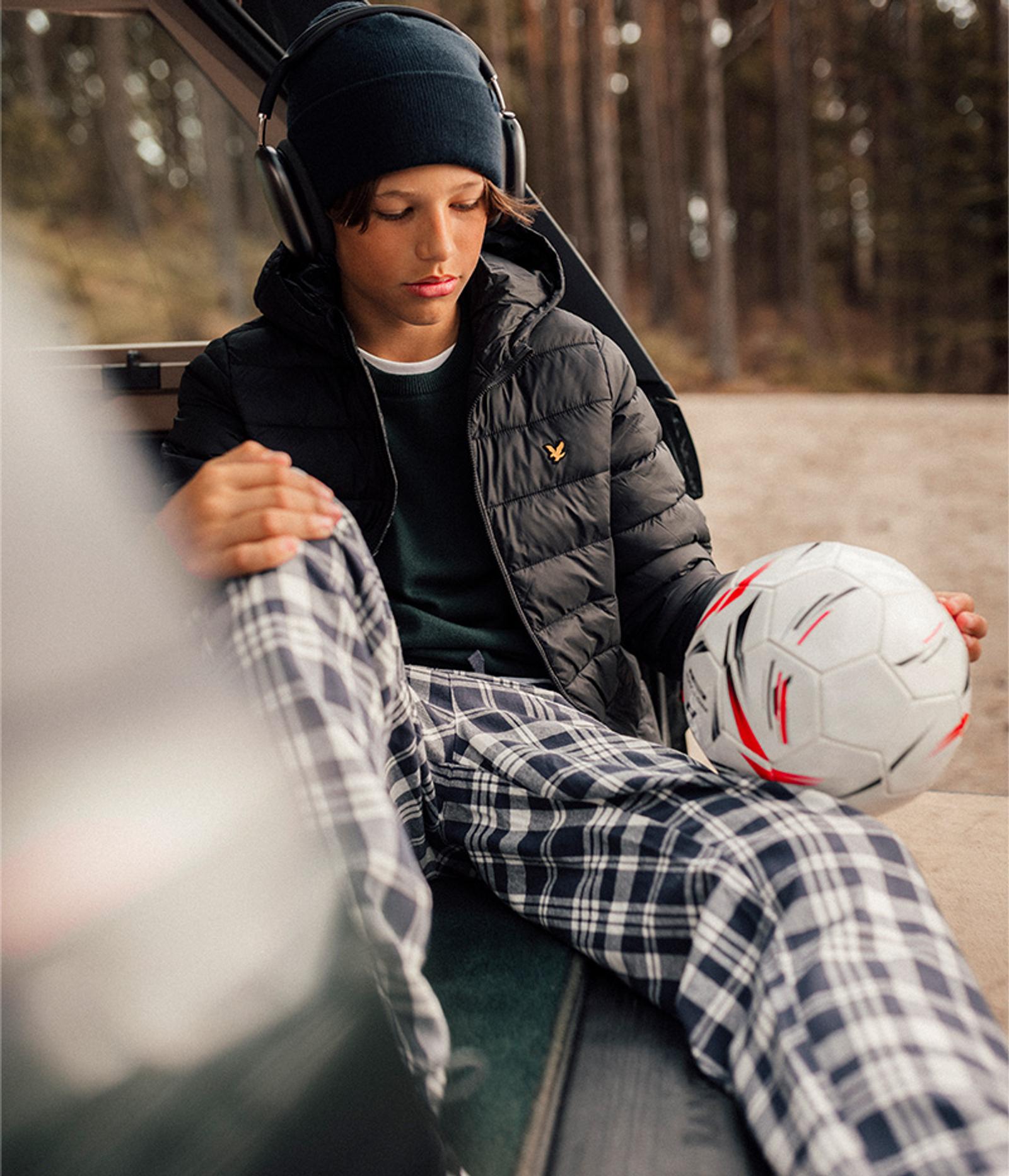 a young boy is sitting in the back of a car holding a soccer ball .