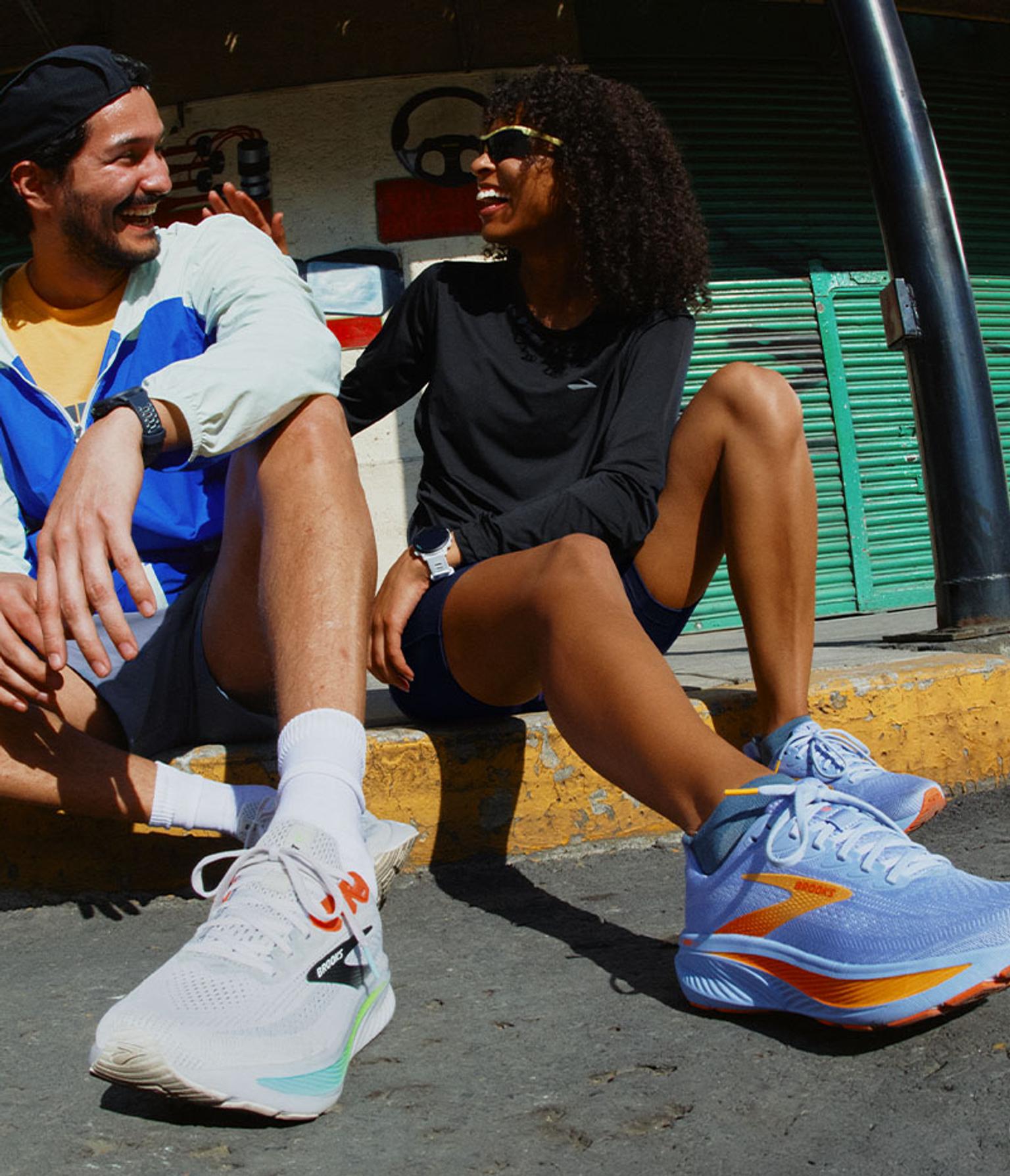 a man and a woman are sitting next to each other on the sidewalk .