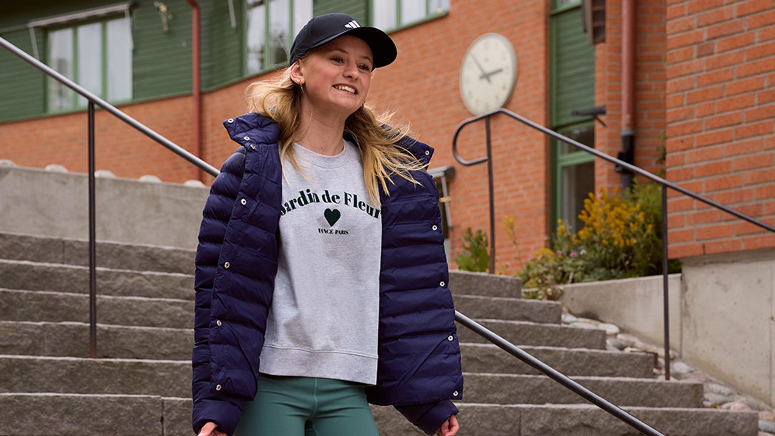 a young girl is standing on a set of stairs wearing a blue jacket .