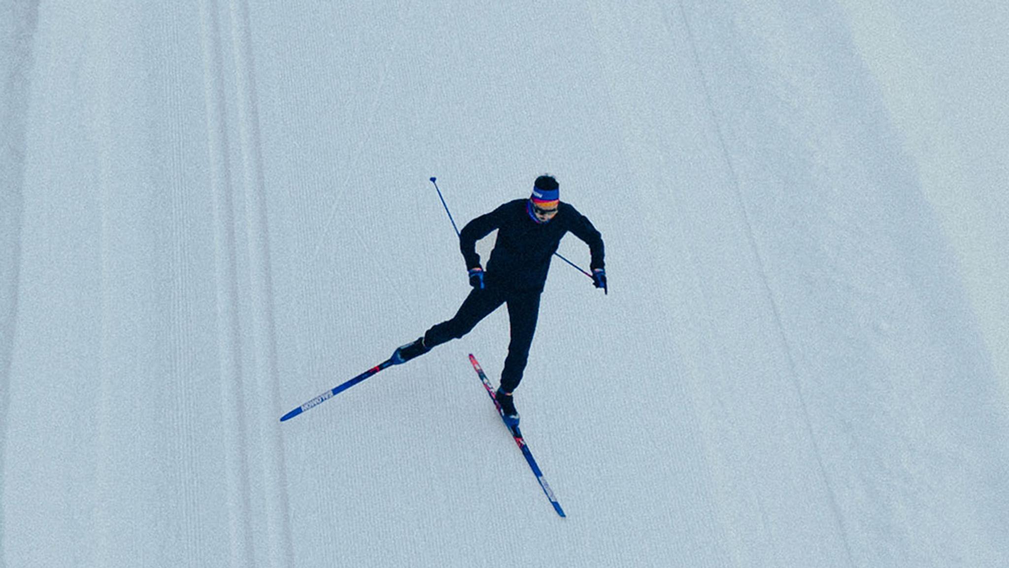 Overhead view of a person cross-country skiing on a groomed snow trail.