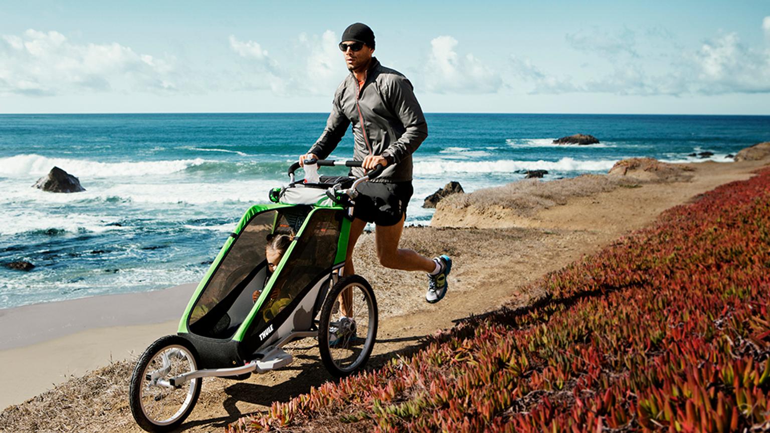 a man is pushing a stroller on a beach near the ocean .
