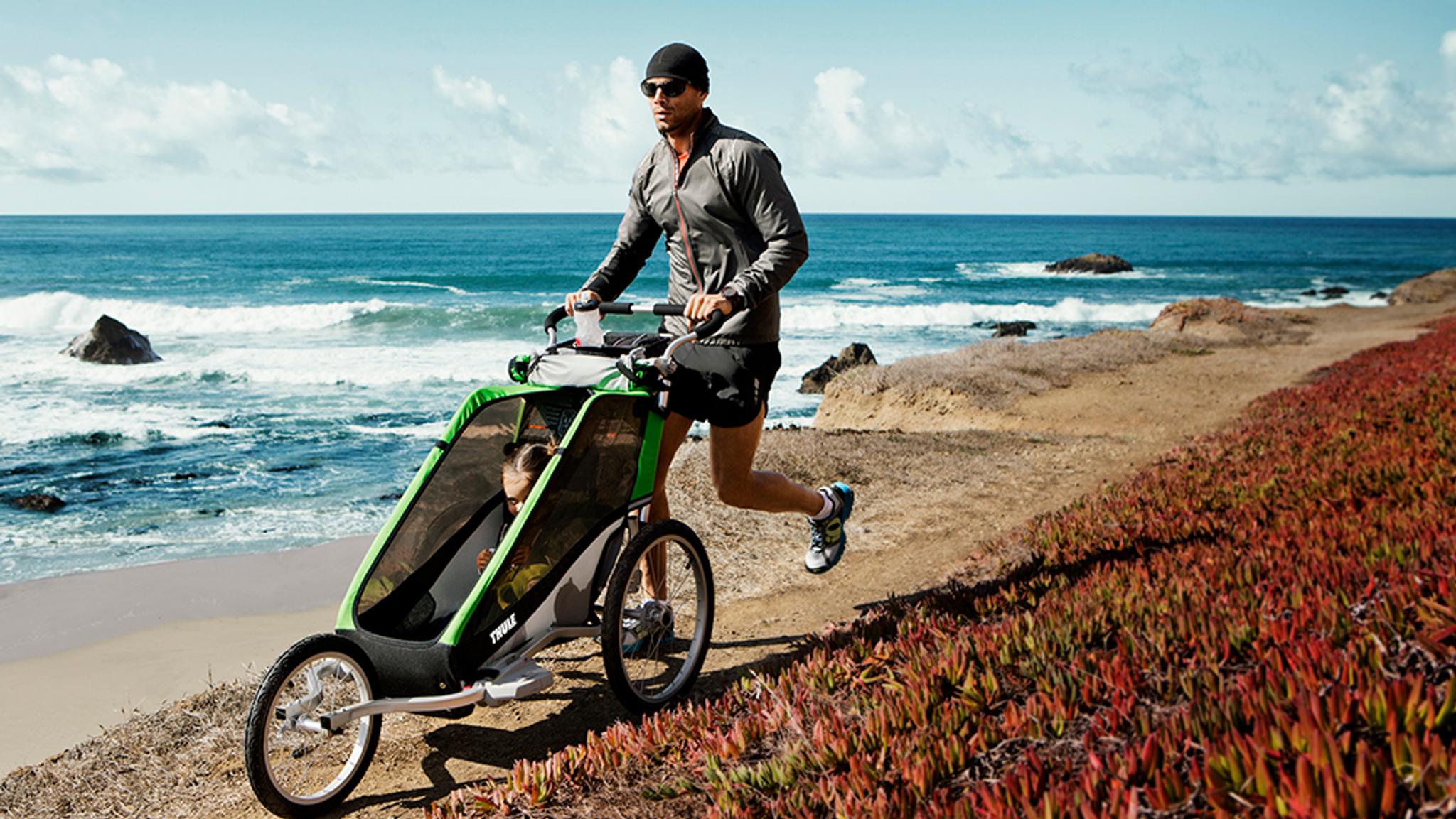 a man is pushing a stroller on a beach near the ocean .