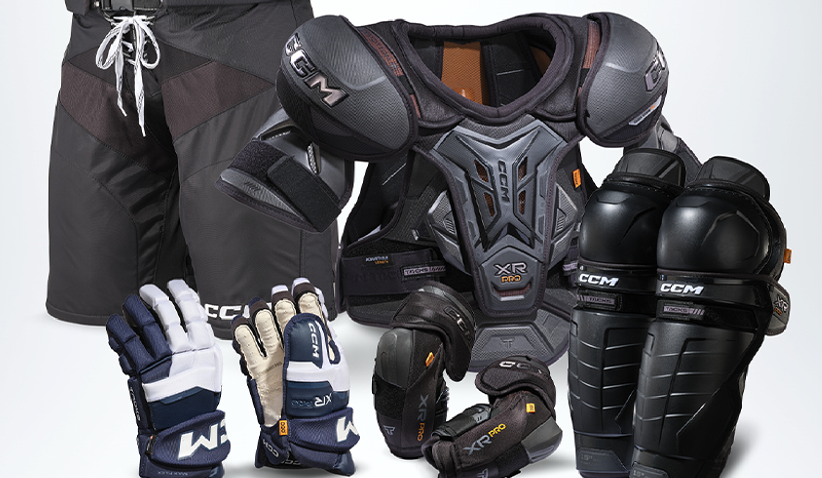 CCM ice hockey protective gear, including black pants, shoulder pads, shin guards, elbow pads, and two pairs of gloves.