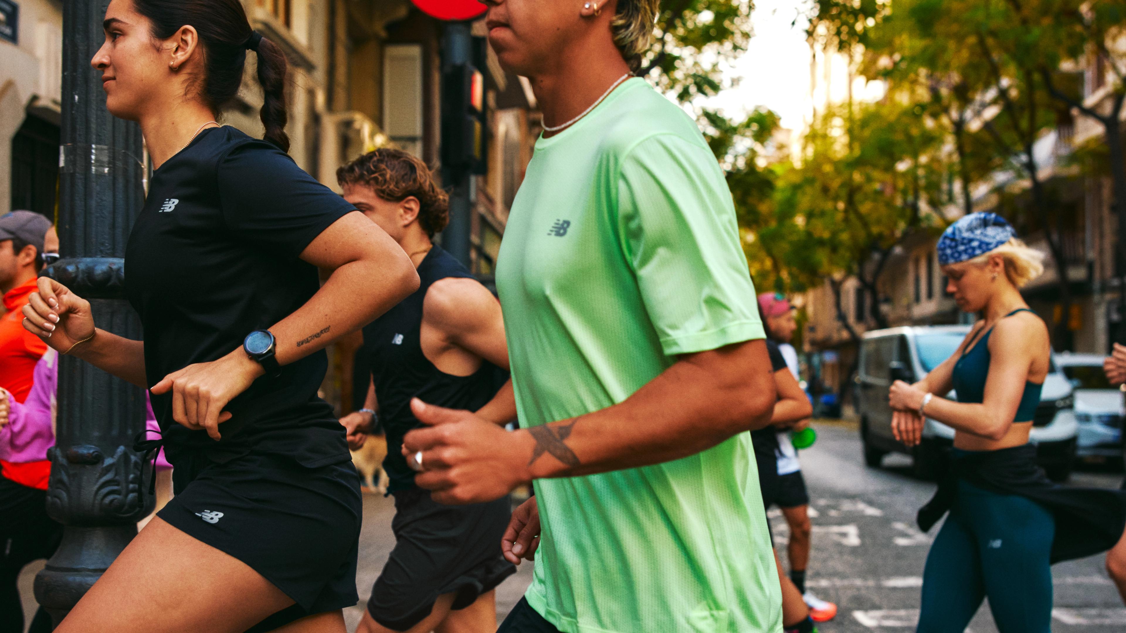 A diverse group of runners wearing New Balance activewear on an urban street.