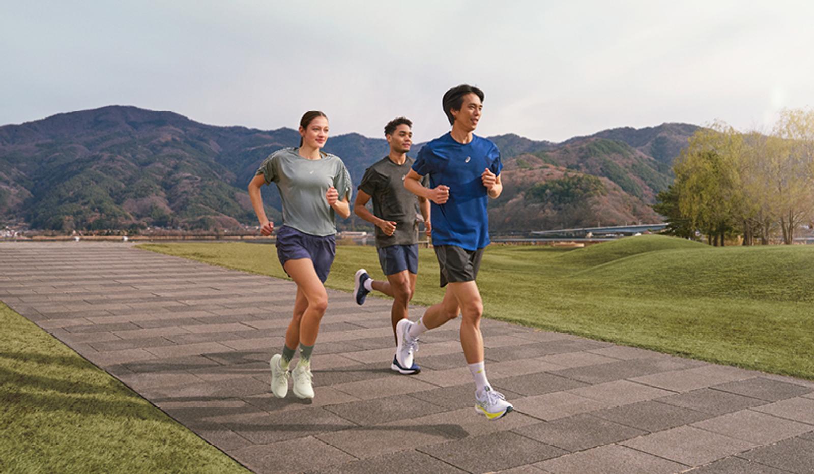 a group of people are running on a sidewalk in a park .